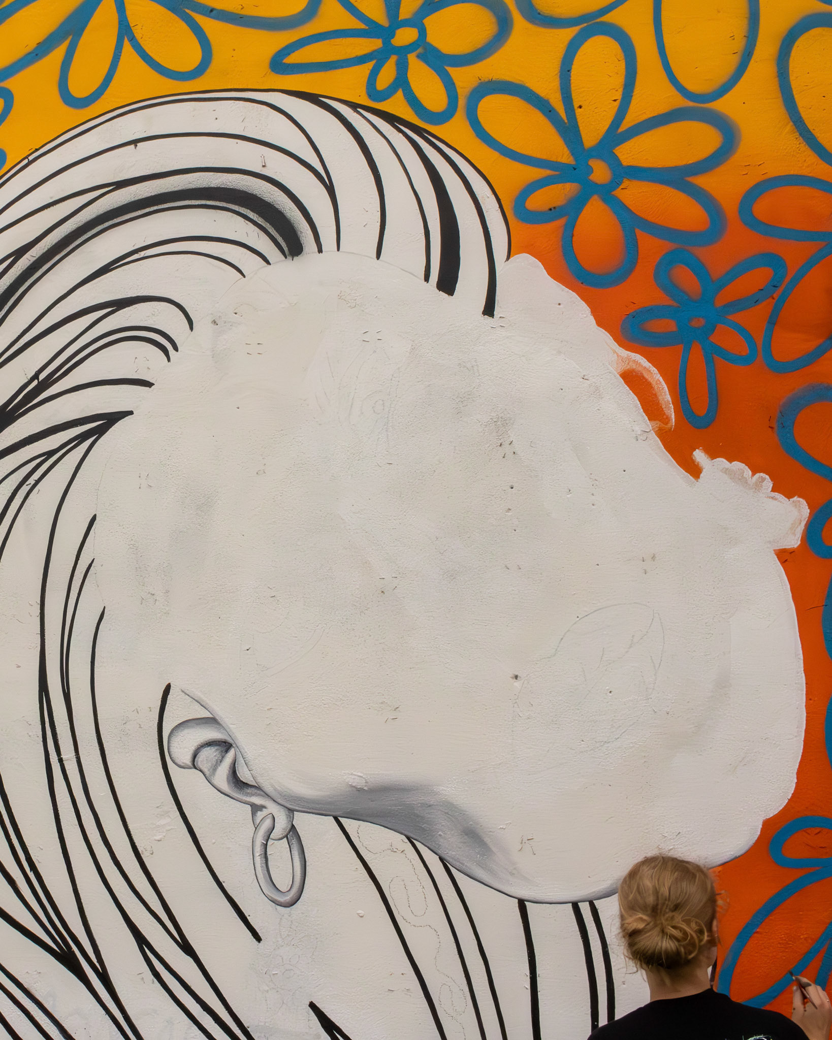 Toledo painter Taylor Meinem working on her mural displayed in East Toledo on 6th and Main Street