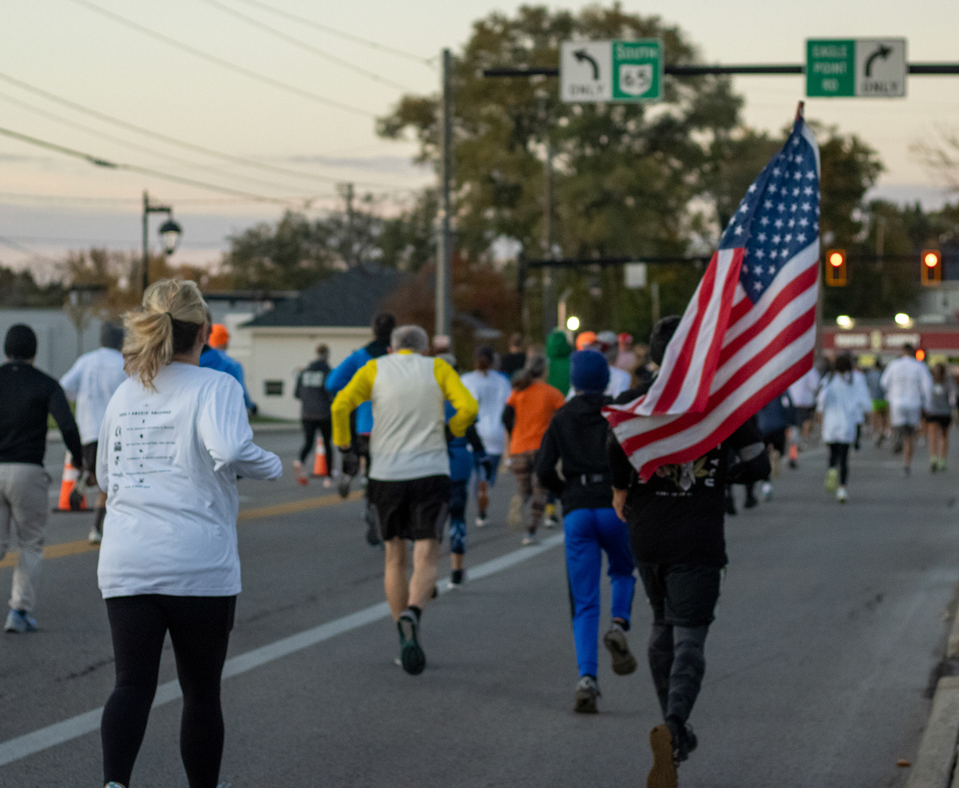 A varied group of runners just moments after the start of the 5k. Marine Jason Portala starts his run proudly carrying an American flag.
