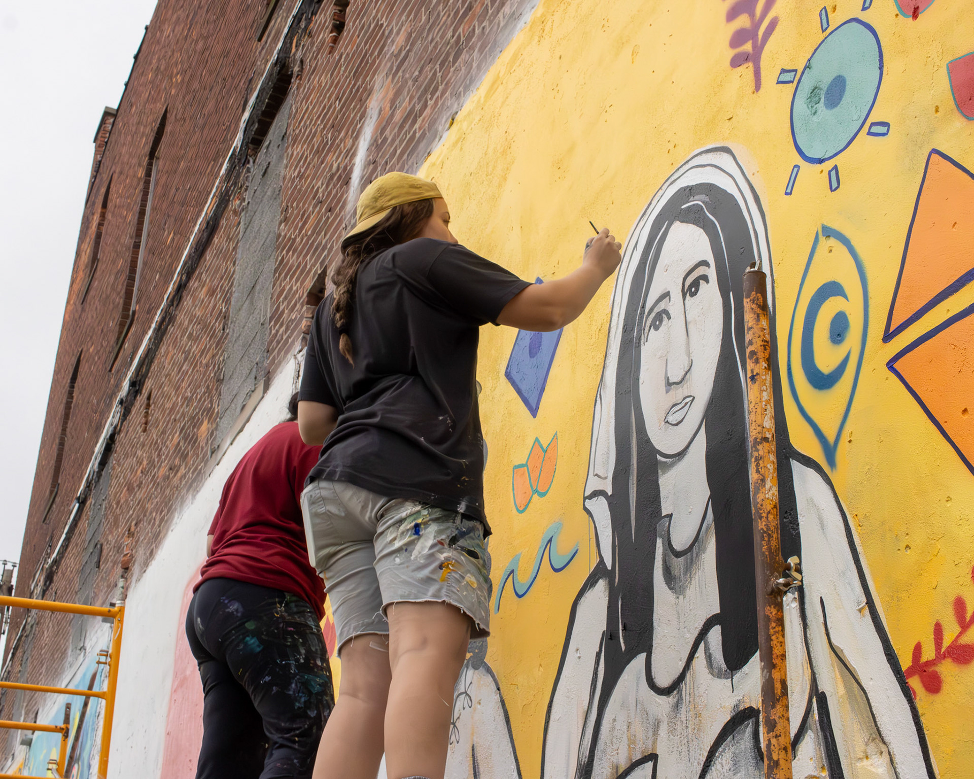 Toledo muralist Caroline Jardine and Reem Barakat work together to complete their mural.