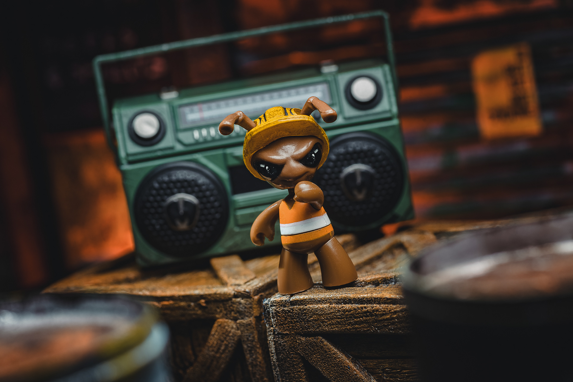 Na zdjęciu widoczna jest figurka Gomez od Mezco Toys, przedstawiająca eleganckiego, humanoidalnego karalucha, który łączy w sobie elementy retro i futurystycznego szpiegowskiego stylu. Gomez ma smukłą sylwetkę, ubrany jest w szykowny, dobrze skrojony garnitur, najczęściej czarny lub ciemny, z krawatem. Jego głowa to owadzie, charakterystyczne oblicze – duże, błyszczące oczy i długie czułki. Często w ręku trzyma pistolet lub inny gadżet szpiegowski, co podkreśla jego tajemniczą i groźną naturę. Figurka stoi w dynamicznej, gotowej do akcji pozie, a szczegółowo wykonane detale i akcesoria nadają jej kolekcjonerski, wysokiej jakości charakter.