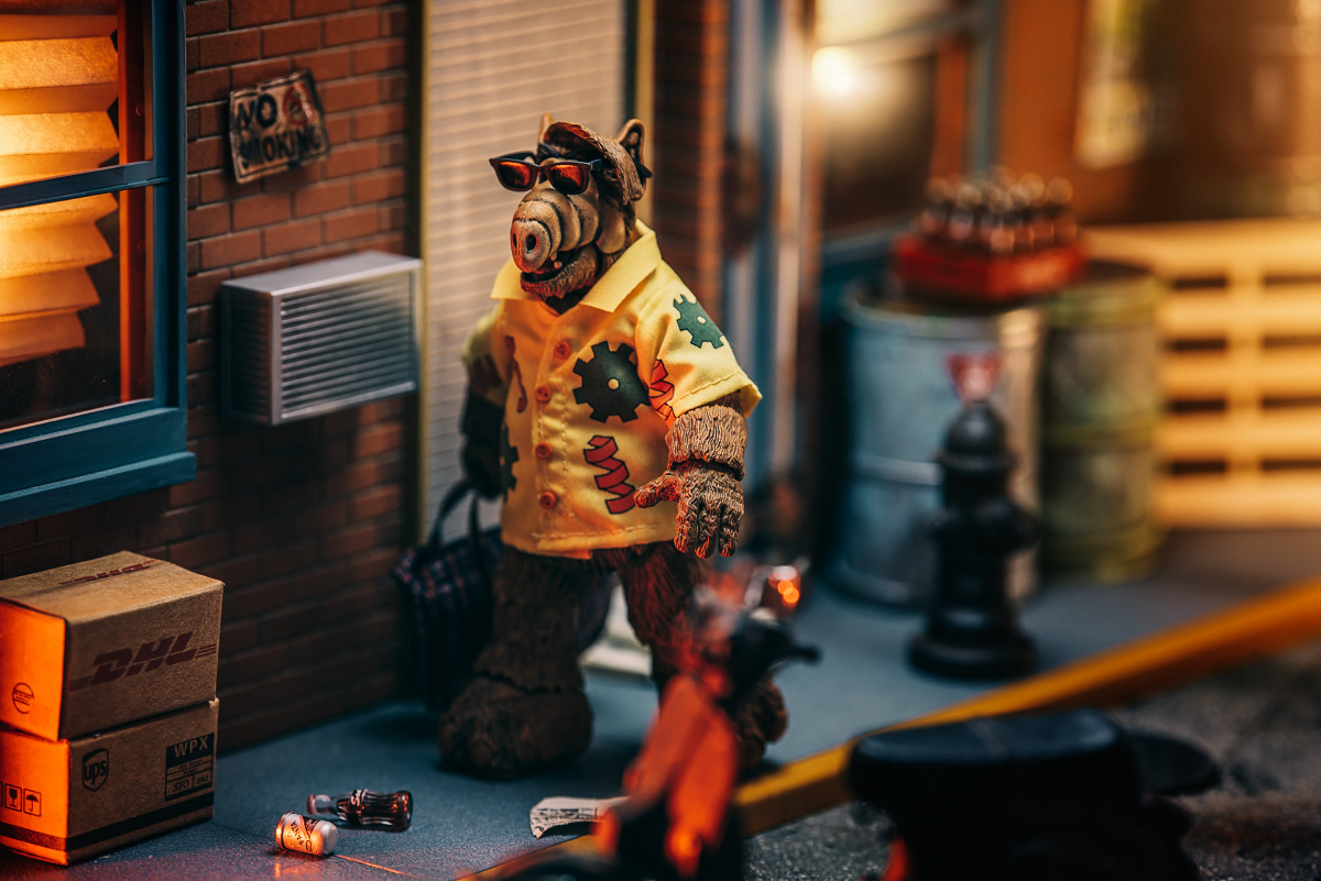 ALF - action figure NECA, Tytułowy bohater Gordon Shumway był małym kosmitą przezwanym A.L.F. (od ang. alien life form, obca forma życia). Urodził się 28 października 1756 r. na fikcyjnej planecie Melmac (6 parseków za Hydra Centauris), która miała zielone niebo i niebieską trawę oraz cierpiała na nadmiar złota i platyny. Alf pokryty był w 98% futrem barwy sjeny palonej, miał pomarszczony pysk, osiem żołądków, a jego ulubiony posiłek stanowiły koty. Wylądował na Ziemi, rozbijając się swoim statkiem kosmicznym na dachu garażu rodziny Tannerów, na przedmieściach Los Angeles, i zamieszkał razem z nimi. Dzieci, Lynn i Brian za nim przepadają, ojciec Willie raczej go toleruje, a z matką Kate często ma na pieńku. W serialu pojawiają się też wścibscy sąsiedzi Ochmonkowie oraz kot Tannerów, Szczęściarz (Lucky), na którego zjedzenie Alf ma wielką ochotę.