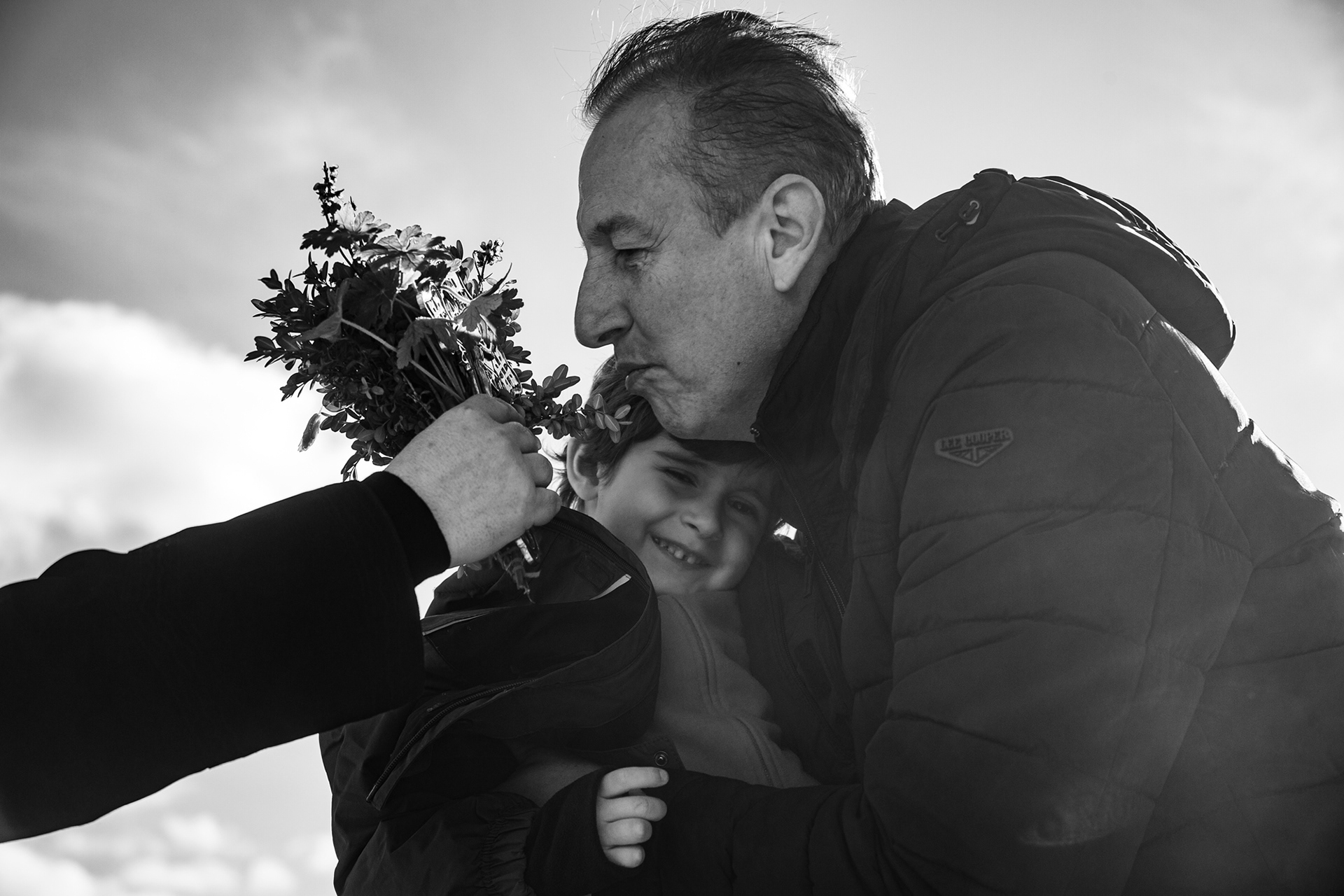 A father and his son kiss the priest's hand as he sprays them with holy water for.
