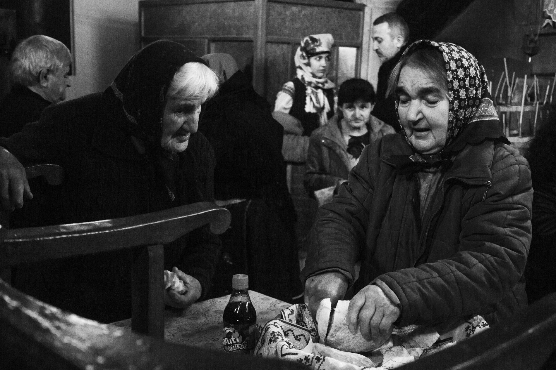 Two elderly women breaking the homemade bread to give to everyone who came to the sermon at the church at the end of the ceremony.