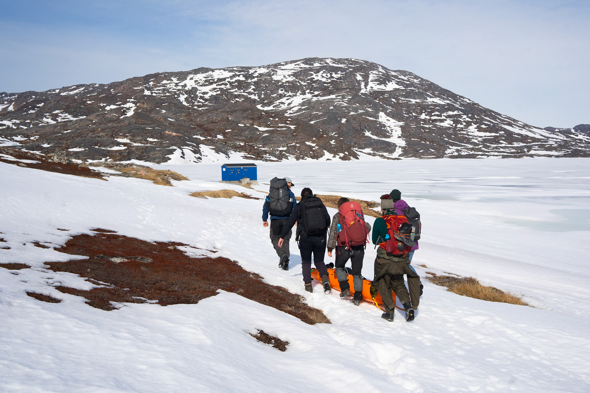 Wilderness first responder training, including dragging someone in a stretcher to safety on the snow.