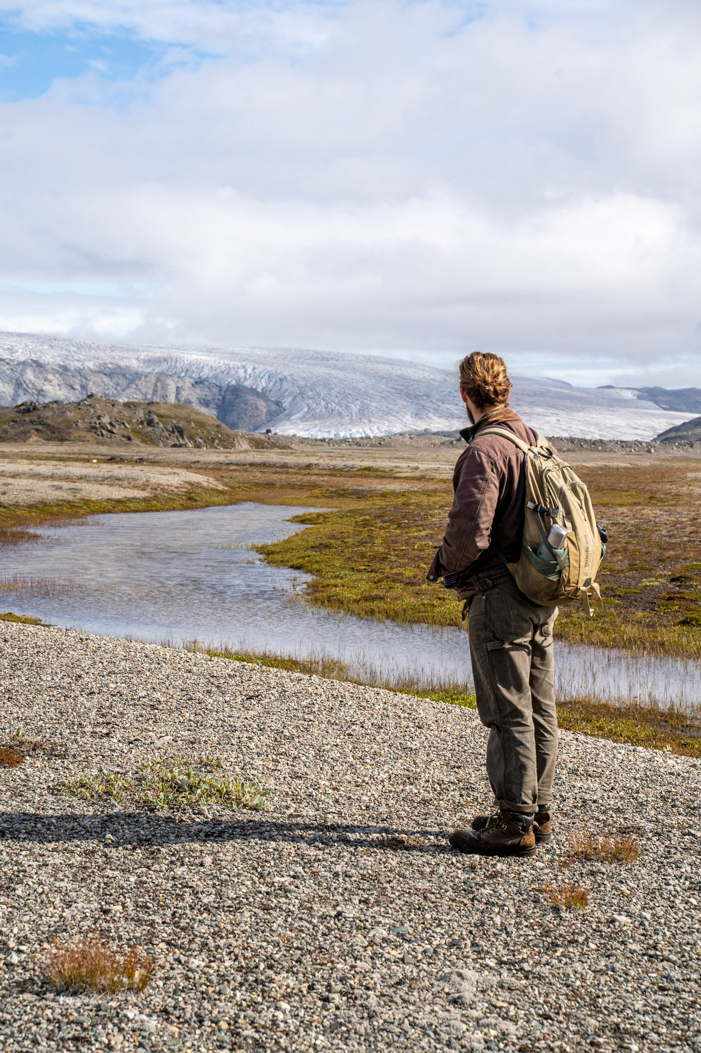 Carson on a gravel field potentially to be used for hay farming. The glacier visible in the background.
