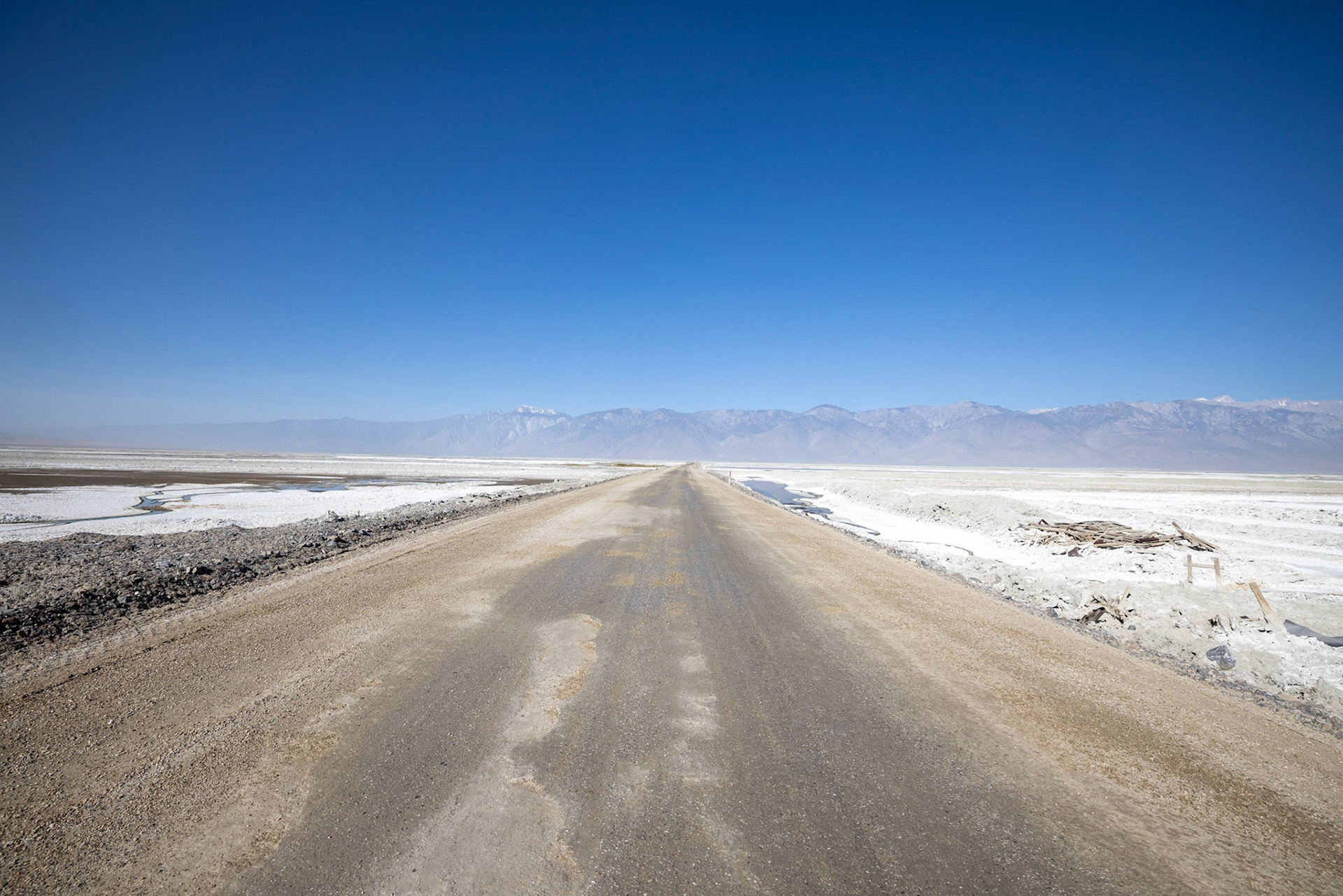American Road dirt road with mountains in the back. On the side is salt of dried up salt lakes