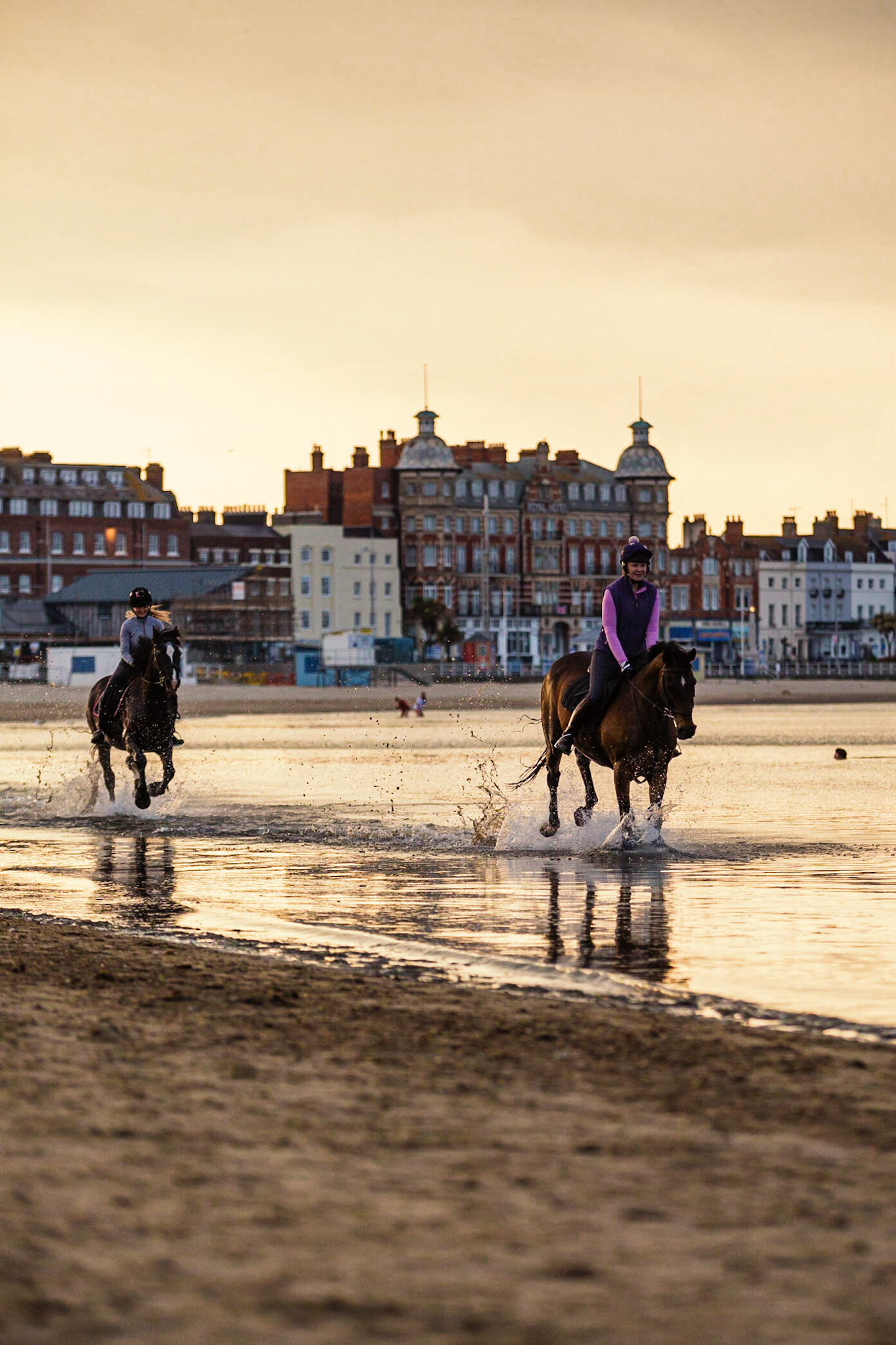 Horses riding along Weymouth Beach in summer