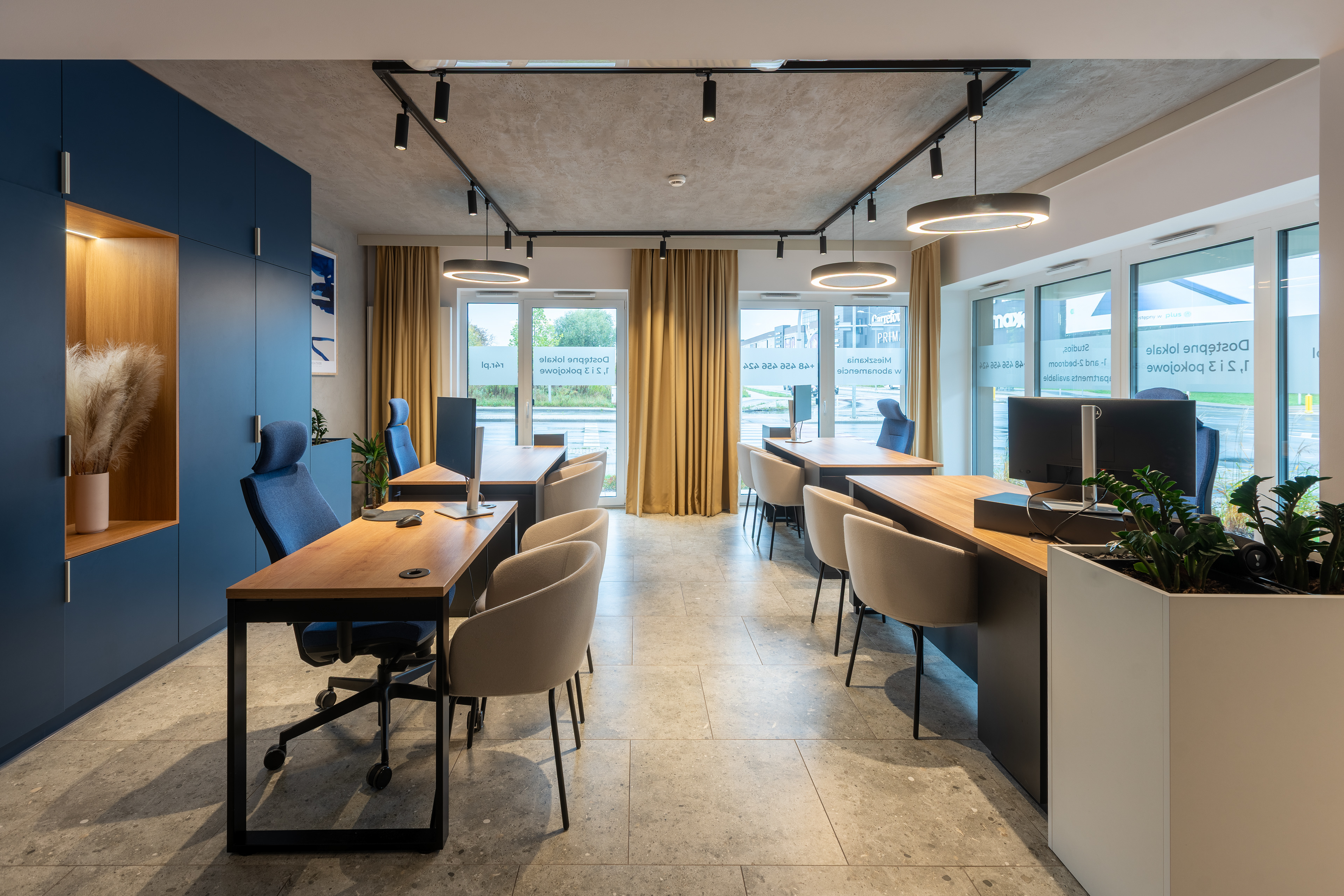 Strefa pracy z drewnianymi biurkami i granatową zabudową – projekt ISA Architekci