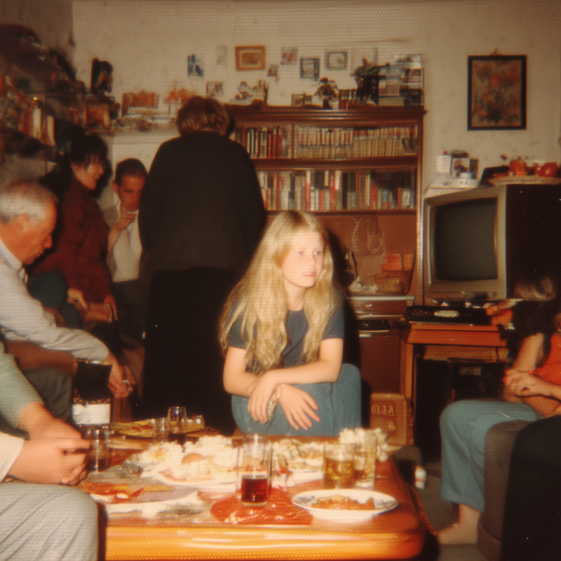 Eigene Darstellung (2025). Familienschnappschuss Familienzusammenkunft[KI-generiertes Bild]. Erstellt mit Midjourney. Prompt: “A grainy, low-quality photo taken with an old disposable camera shows the family sitting around the living room table for dinner. A blonde teenager in a blue dress and her pregnant mother are seated at the table. In the background, the grandmother is seated in a sofa chair, and the grandfather is holding a cup of tea.”