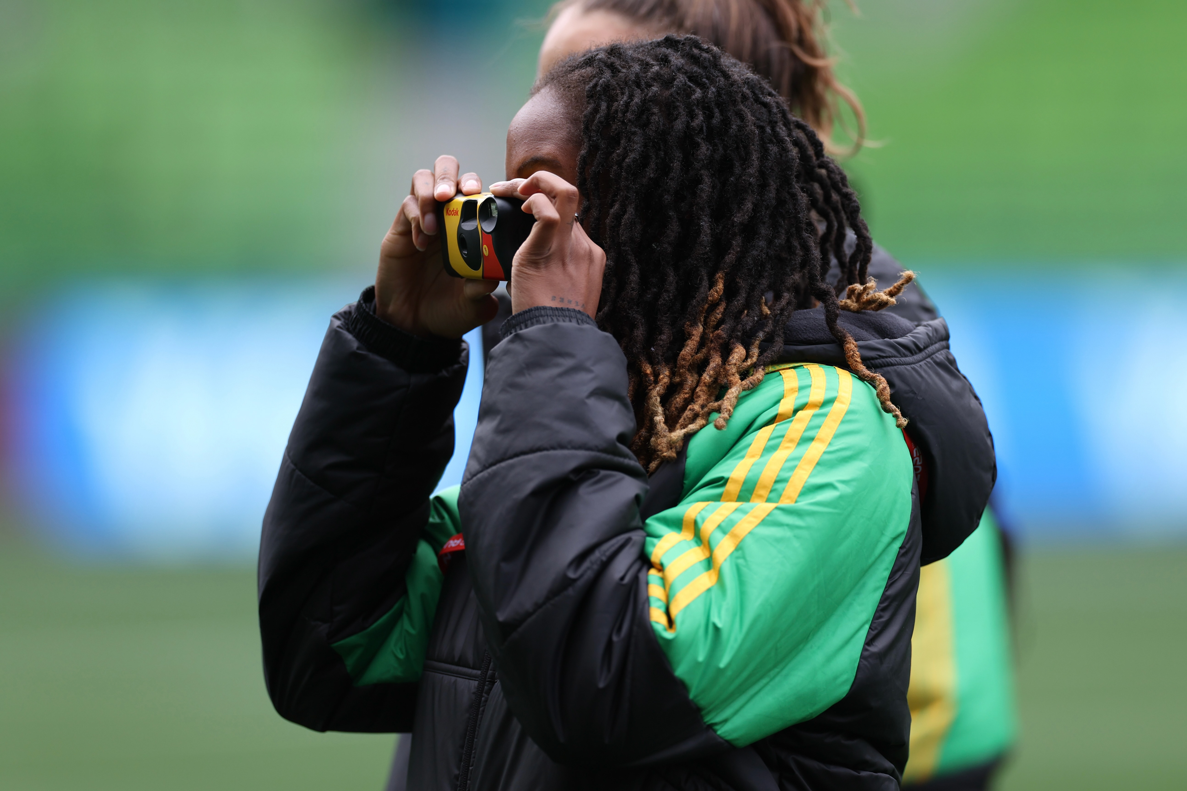 Jamaica's Paige Bailey-Gayle takes a photo on a disposable camera during a familiarization visit to Melbourne Rectangular Stadium ahead of the Women's World Cup Group F match against Brazil in Melbourne, Australia, Tuesday, Aug. 1, 2023. Two crowd funding project have raised more than $98,000 to support the team through the tournament. (AP Photo/Victoria Adkins)