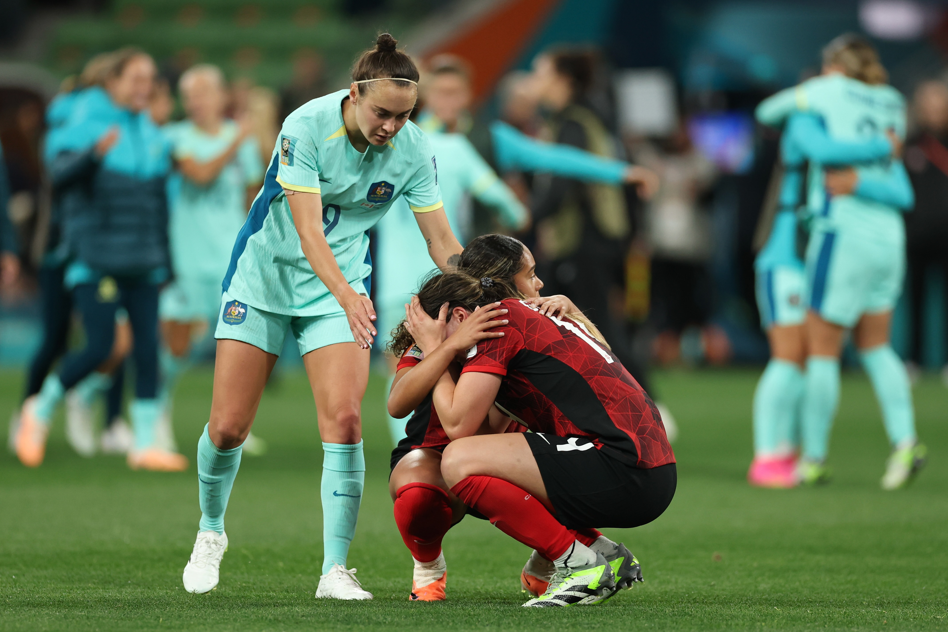 Australia's Caitlin Foord, left, reaches out to Canada's Vanessa Gilles and Olivia Smith at the end of the Women's World Cup Group B soccer match between Australia and Canada in Melbourne, Australia, Monday, July 31, 2023. Australia won 4-0. (AP Photo/Victoria Adkins)