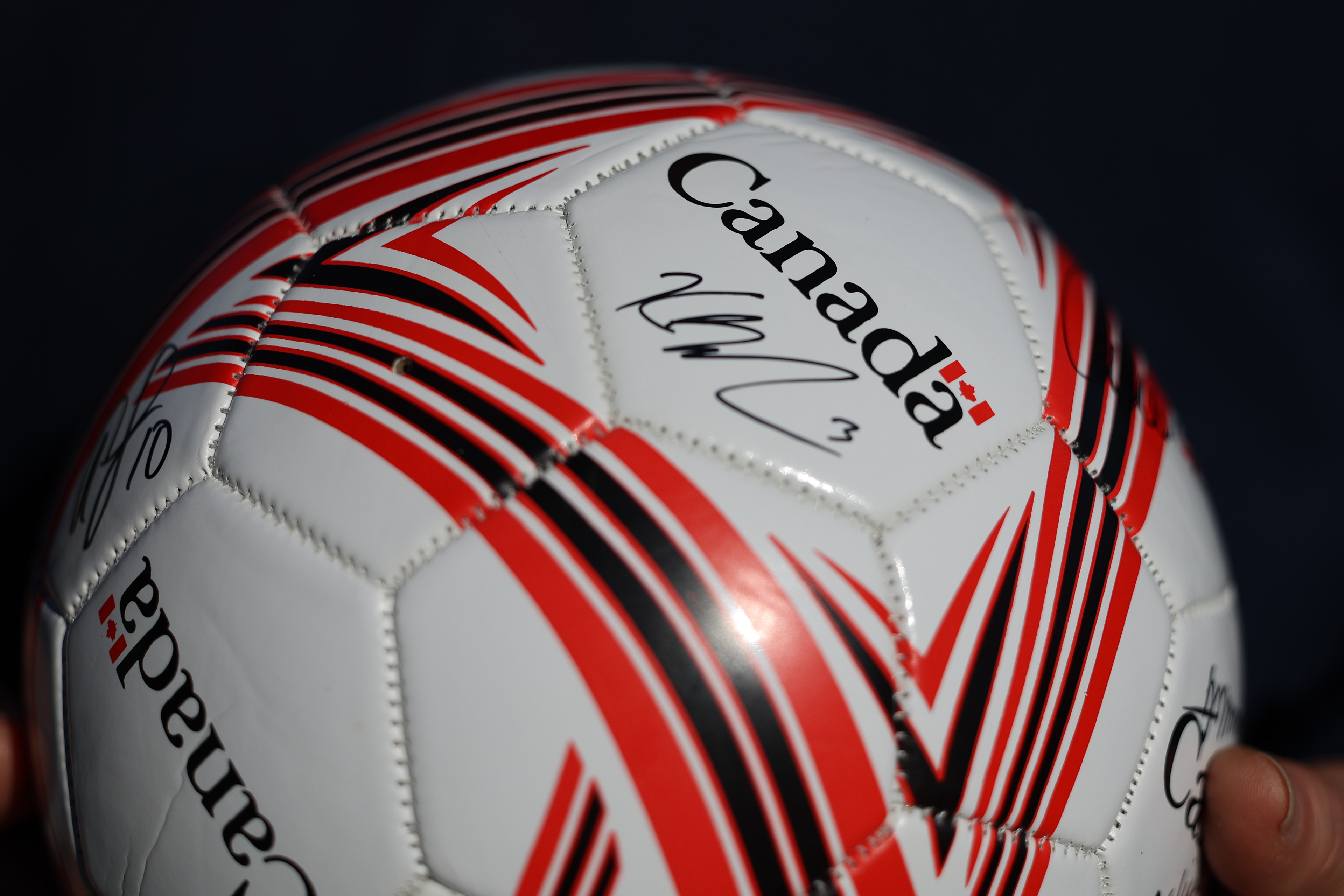 A ball signed by Canada's Kadeisha Buchanan, is held as fans wait for more players to sign following a practice session ahead of the Women's World Cup in Melbourne, Australia, Monday, July 17, 2023. Canada's public training session ahead of its opening match at the Women's World Cup was one of many held by competing teams in co-host Australia. (AP Photo/Victoria Adkins)