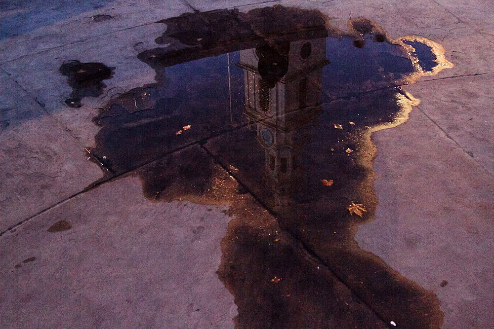 Die Kirche St. Martin-in-the-Fields spiegelt sich nach einem Regenguss in einer Pfütze