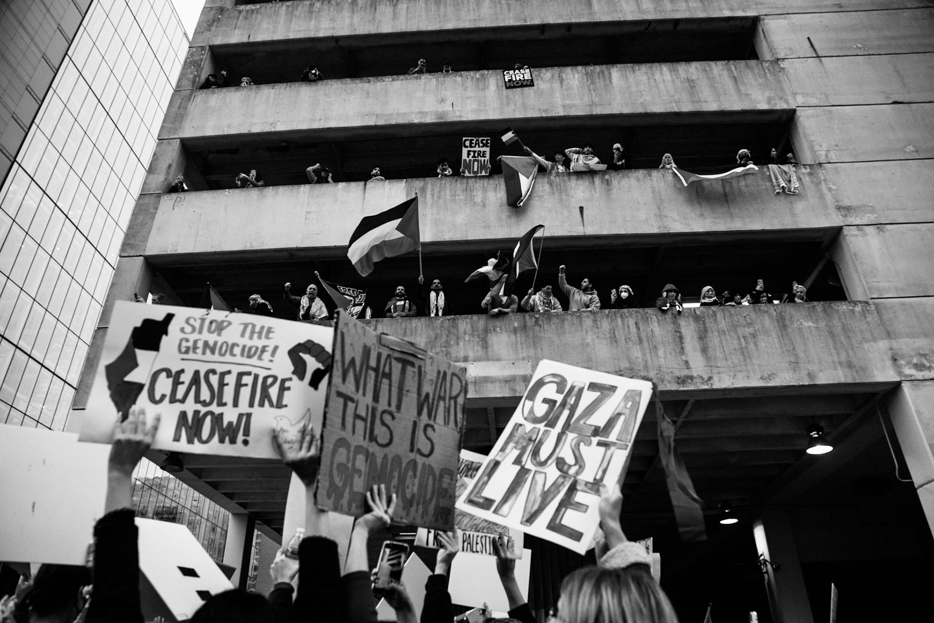 Protestors chant and holler from the parking garage to the marchers below in downtown Austin on Sunday. Thousands called for an immediate ceasefire in Palestine, an end to the United States' aid to Israel and an end to the siege on Gaza.