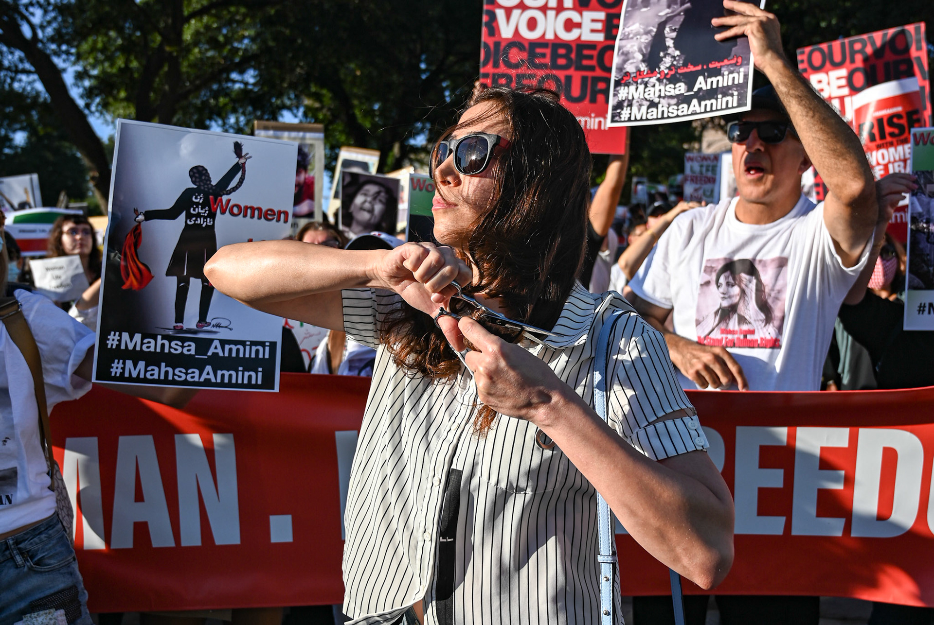 A demonstrator cuts their hair in protest over Mahsa Amini's death in front of the Texas State Capitol on Sept. 26, 2022.