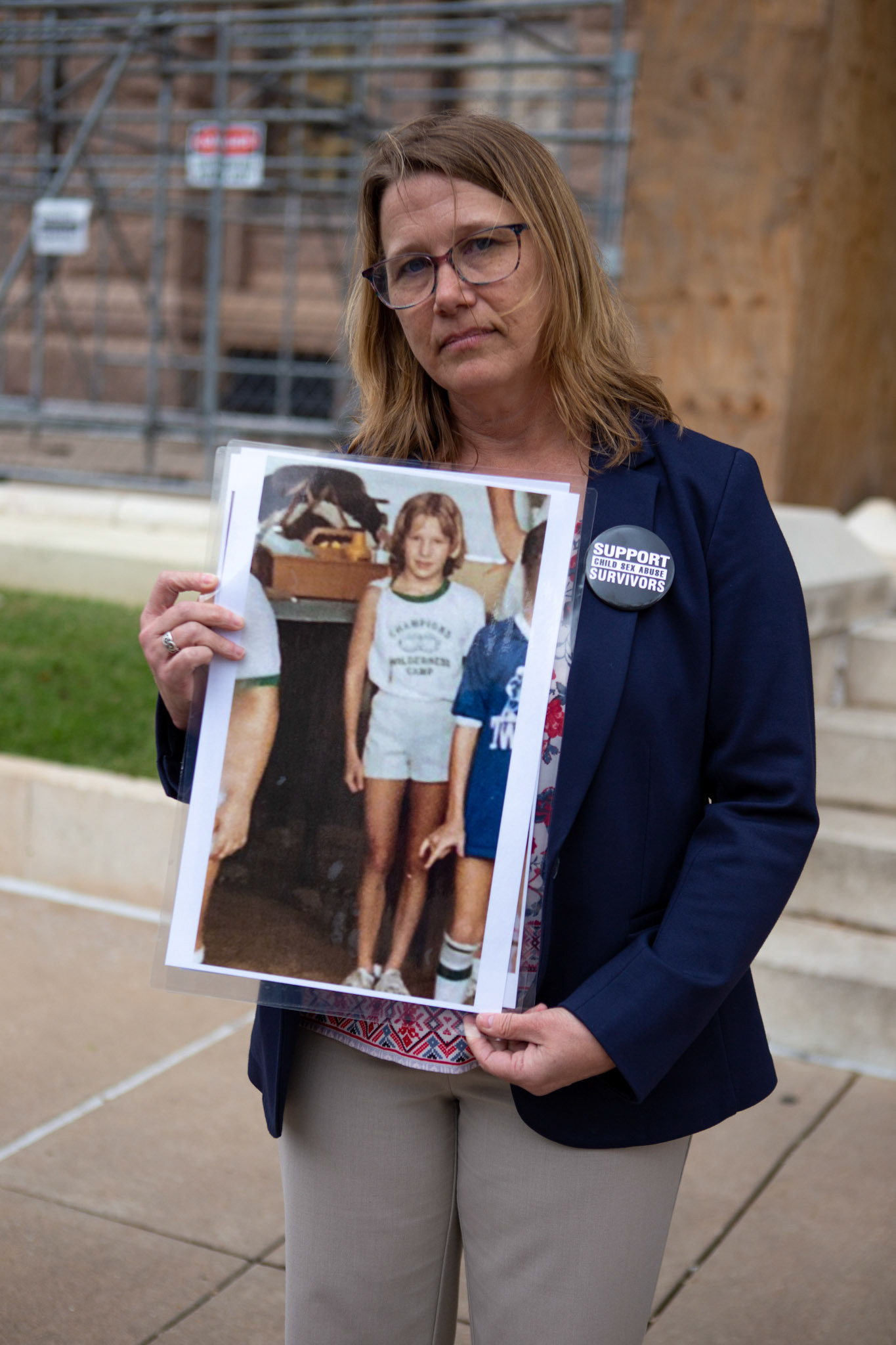 Anne Elrod Whitney from the Texas Survivor Coalition holds an image of her at 10-years-old, when she was sexually abused by her gymnastics coach, on the State Capitol steps on Mar. 22, 2023. “At that time, I didn't really understand what had happened,” Whitney said. “When I started telling people, although people cared, they didn't respond in a way that got any attention.”