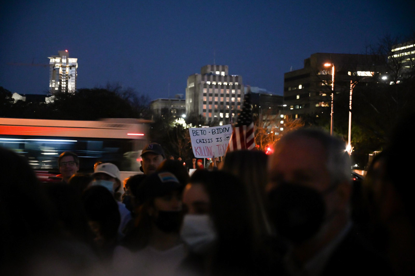 A protester holds a sign reading "Beto-Biden crisis is killing Texans" behind the crowd at the Beto O'Rourke rally on Feb. 9, 2022. O'Rourke advocated for an improved state power grid and addressed issues such as homelessness and access to healthcare in his speech.  