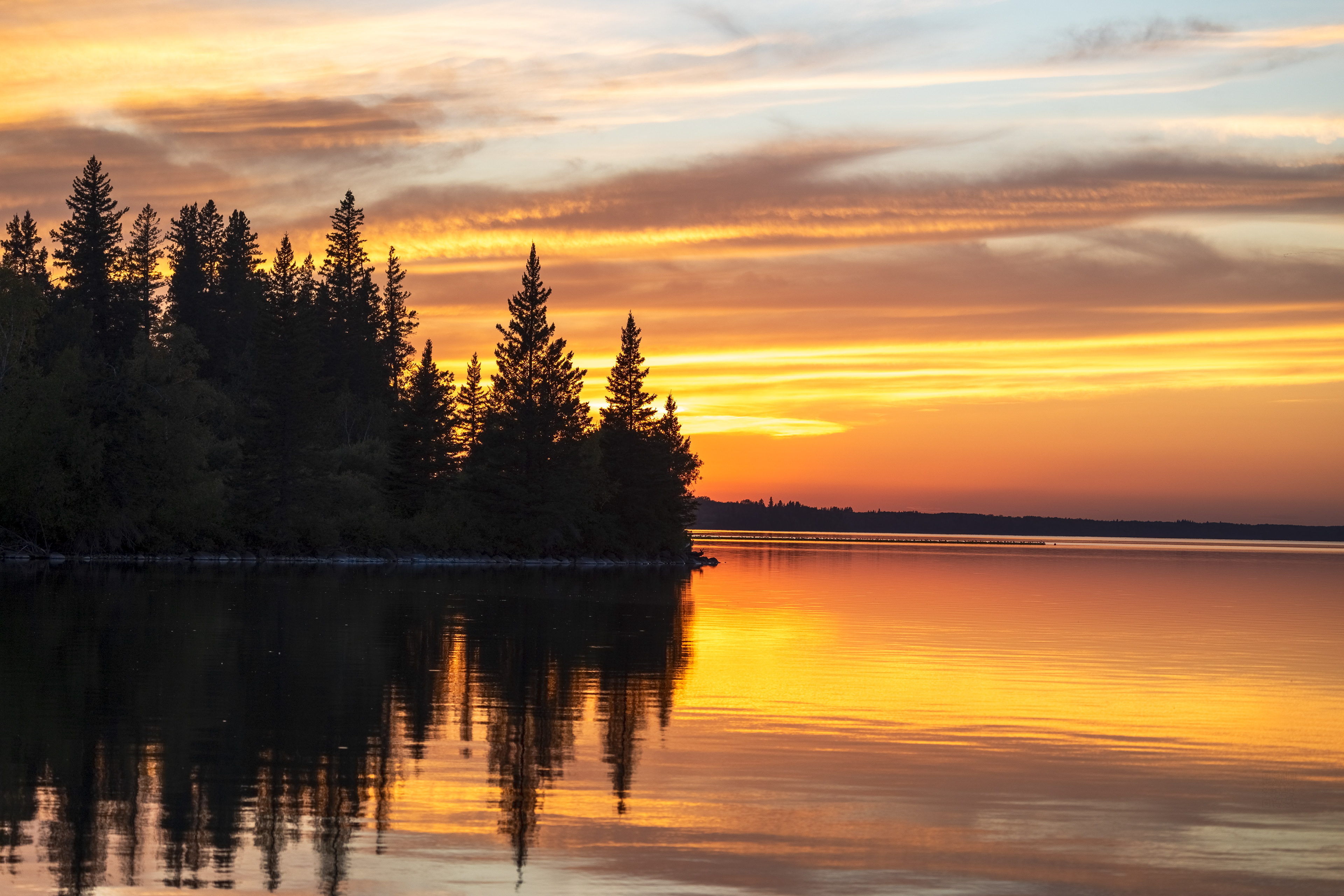 Clear Lake near Minesing, Manitoba — a quiet sunset mirrored in still water and fading trees.