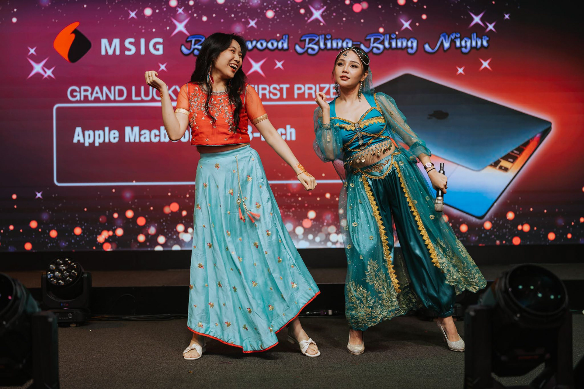Emcee dancing with guests on stage at a Bollywood Bling Bling Night theme dinner, creating an energetic and lively atmosphere.