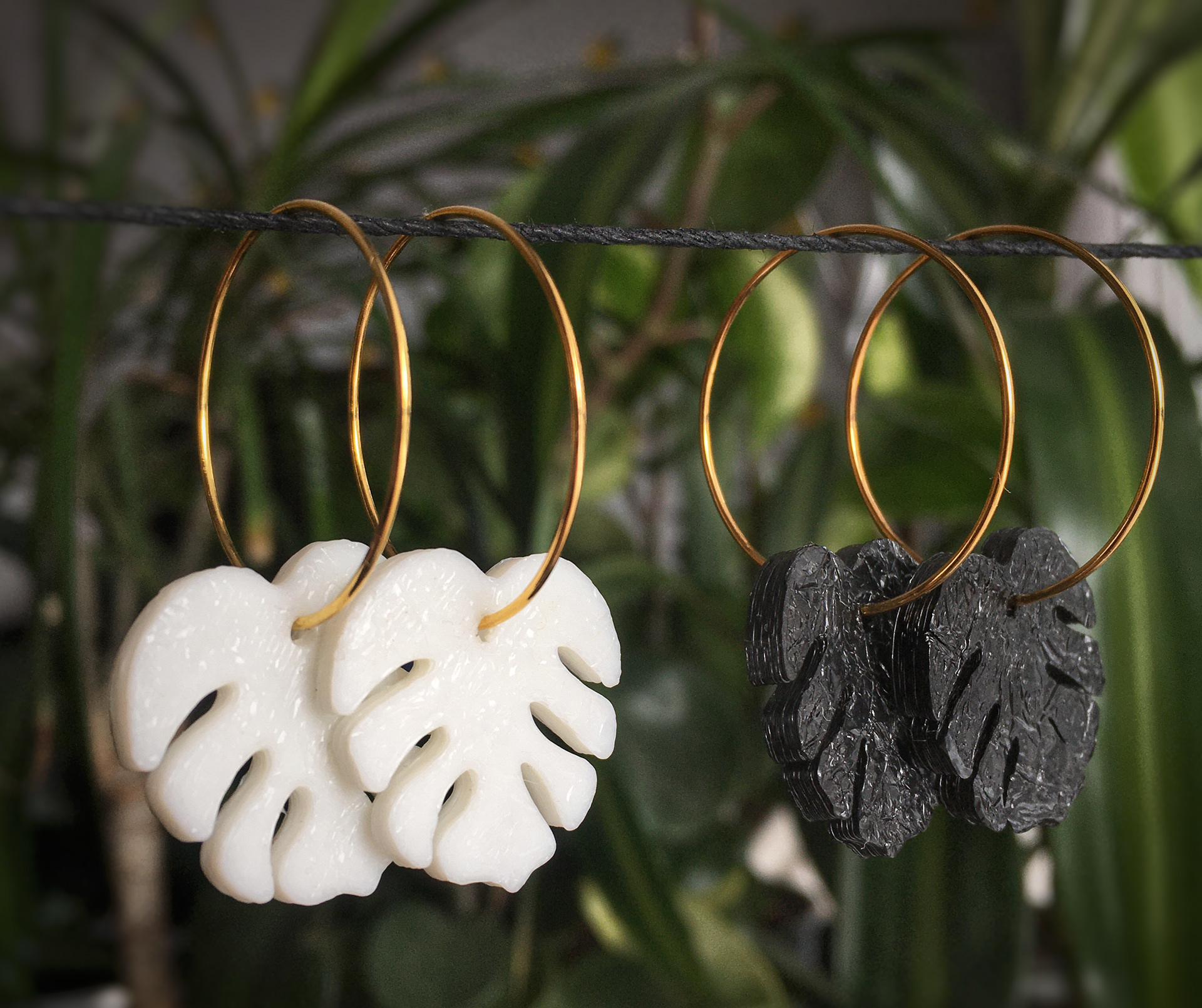 White and black leaf pendants hand on earring hoops.