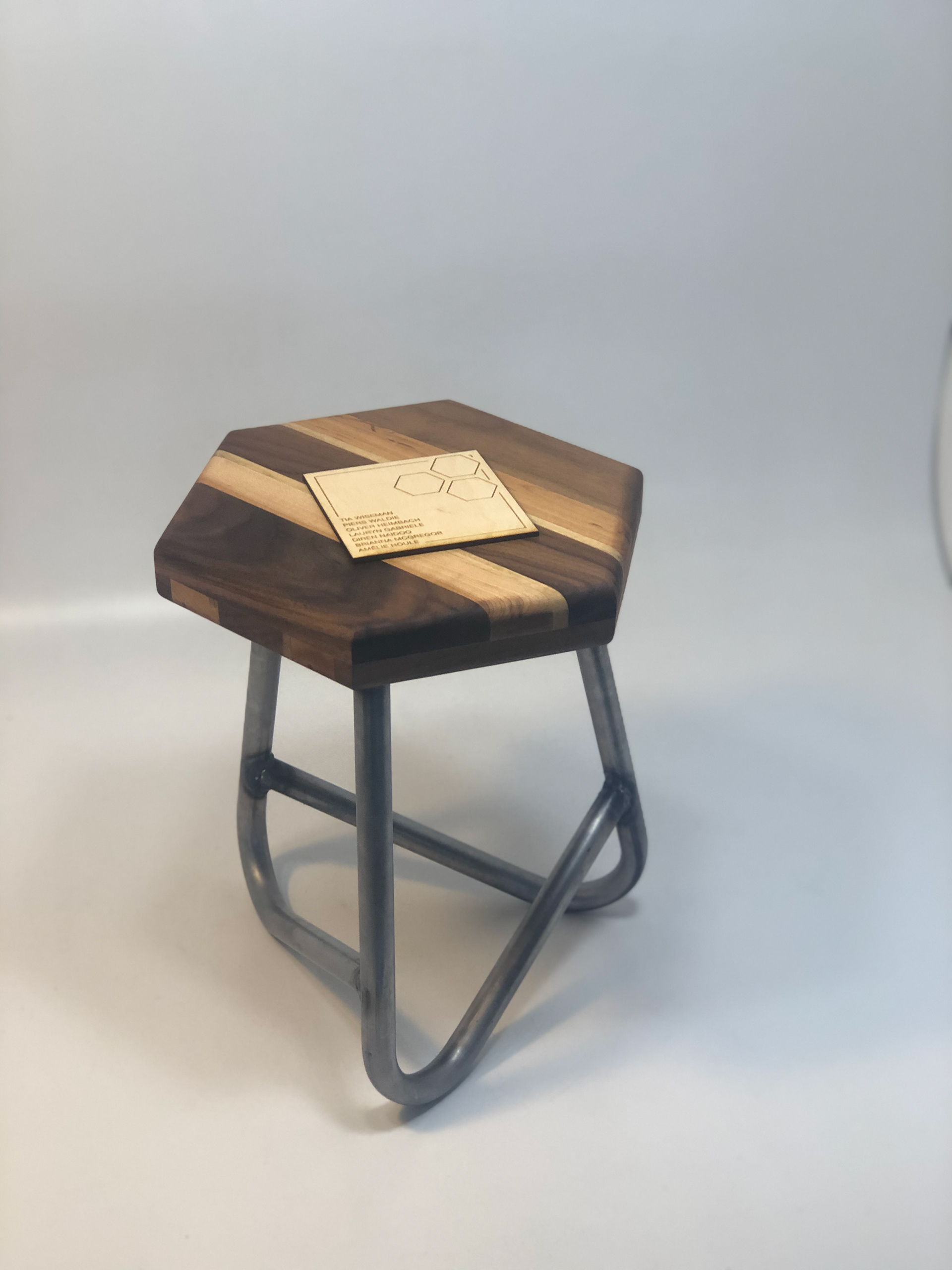 Final children's stool sitting in front of a white backdrop, with a placard with the group members' names on it placed on top of the seat.