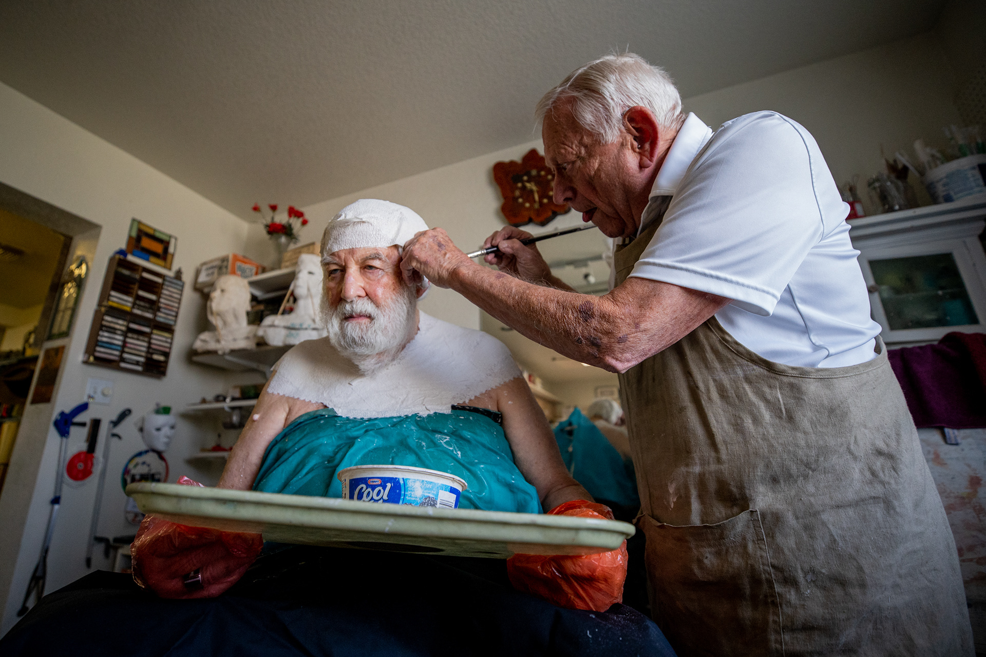 Artist Robert Sutz layers strips of wet plaster bandages onto Holocaust survivor Werner Salinger’s face at his art studio in Scottsdale on Feb. 12, 2022. The material takes about 40 minutes to dry. (Photo by Samantha Chow/Cronkite News)