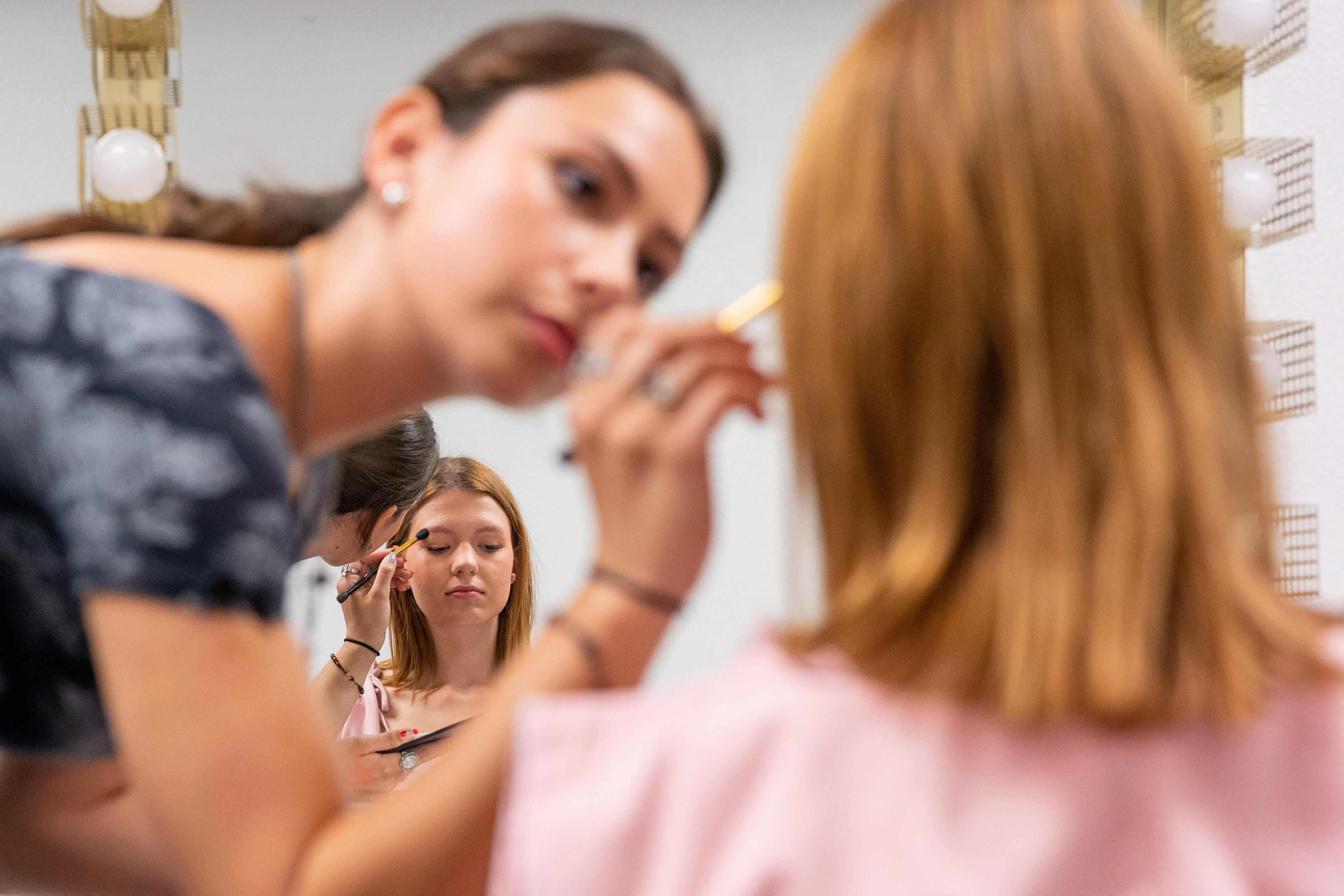 First year business marketing major Elena Needs (left) applies eyeshadow on second year fashion merchandising major Halle Sweeter for the Style Line Spring Fashion Show at F.A.B.R.I.C. in Tempe on April 1, 2022. This was the magazine’s first-ever fashion show and was completely run by students. (Samantha Chow/Arizona State University)