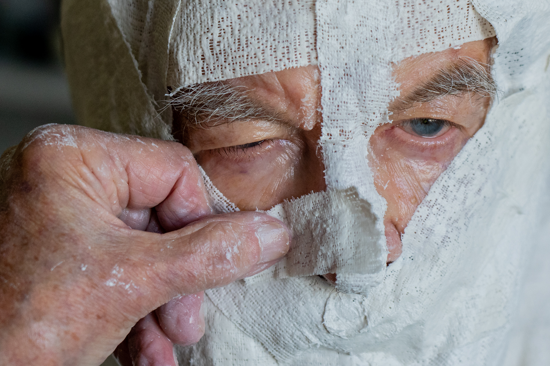 Artist Robert Sutz uses his thumb to shape a plaster bandage around Holocaust survivor Werner Salinger’s nose at his studio in Scottsdale on Feb. 12, 2022. (Photo by Samantha Chow/Cronkite News)