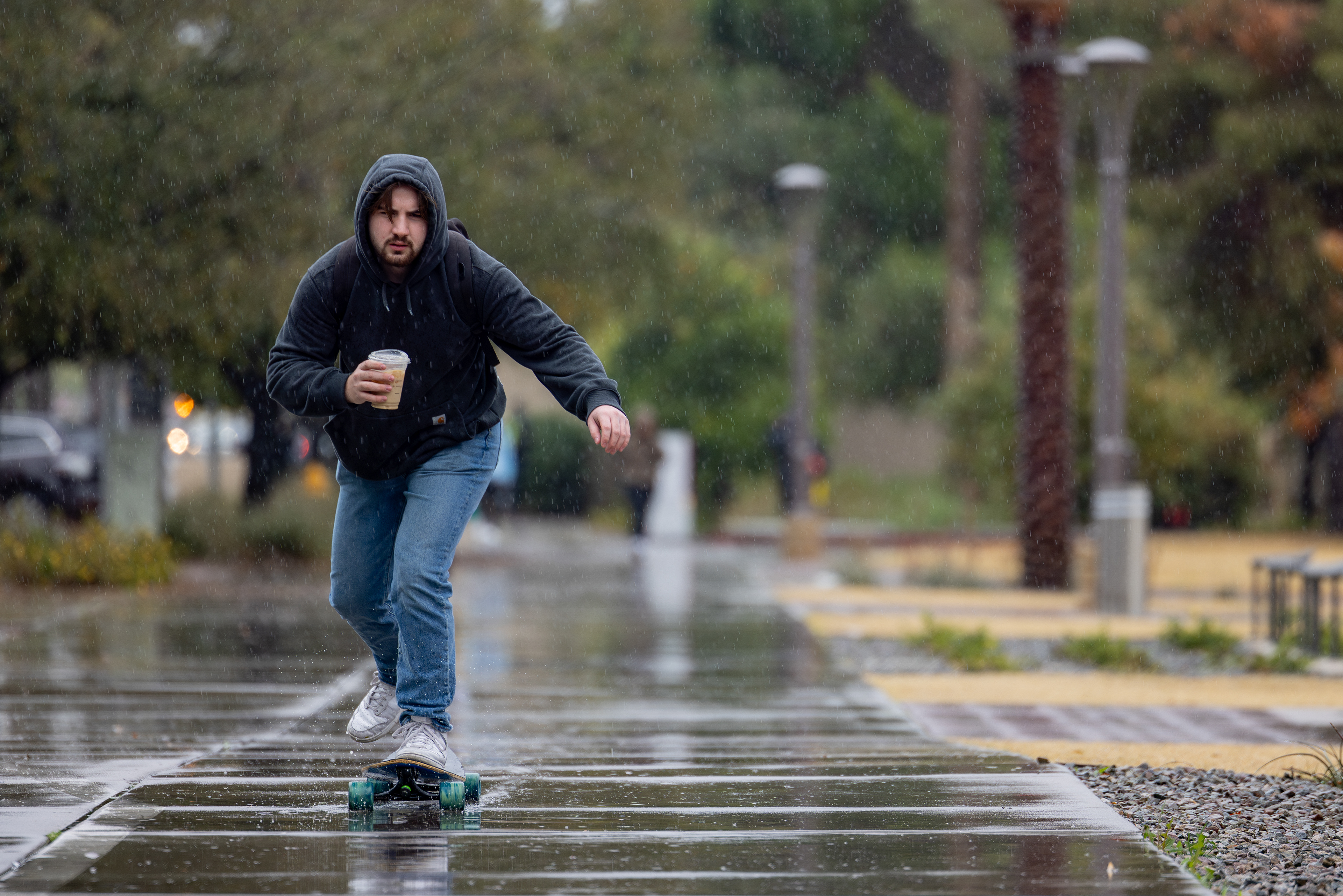 A student skateboards in front of Alumni Lawn as it rains in Tempe on Jan. 23, 2024. (Photo by Samantha Chow/Arizona State University)
