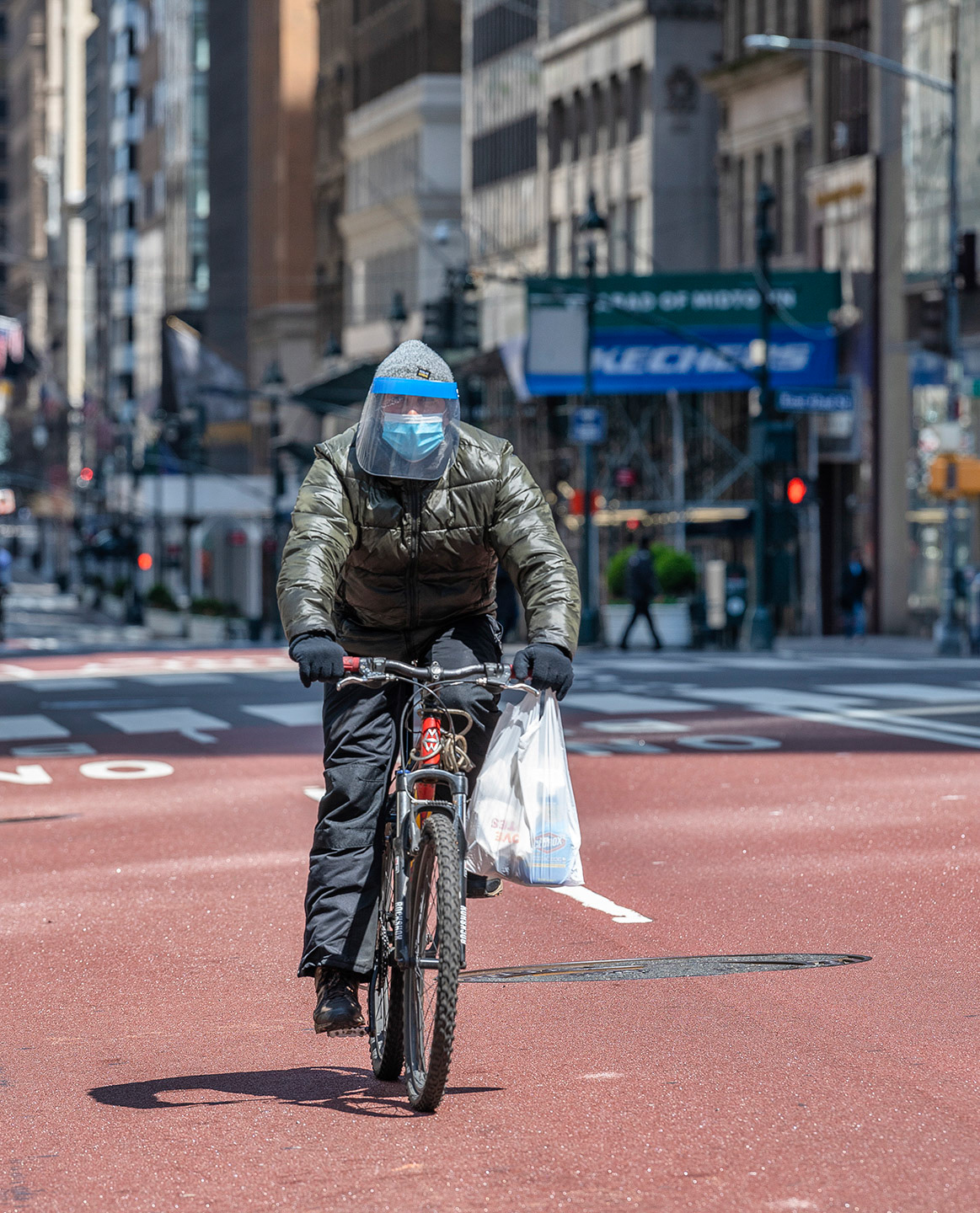 Lone cyclist covered in full PPE during COVID19 lock down in the middle of 5th Ave.