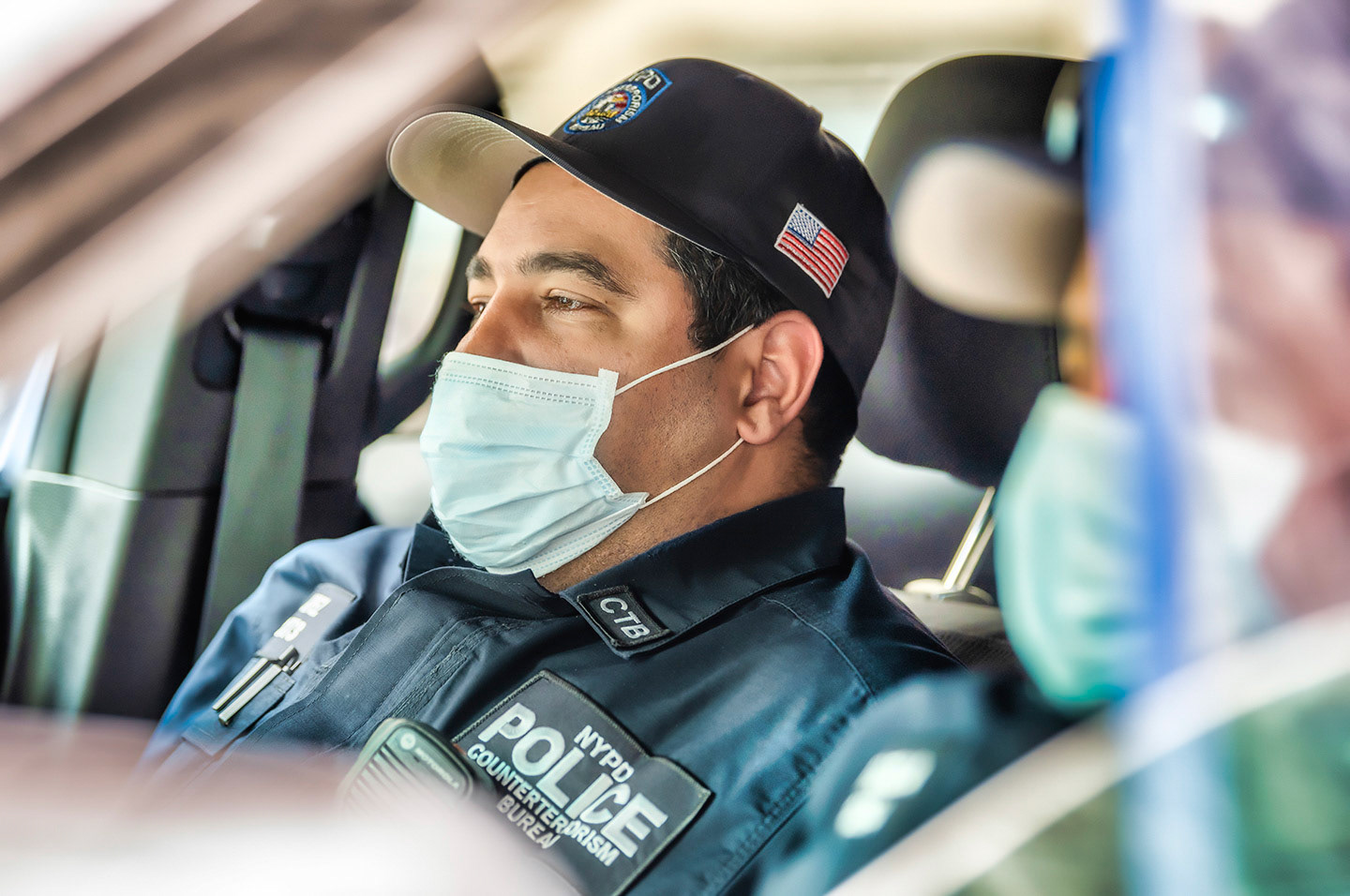 NYPD officer in squad car with COVID19 surgical mask on.