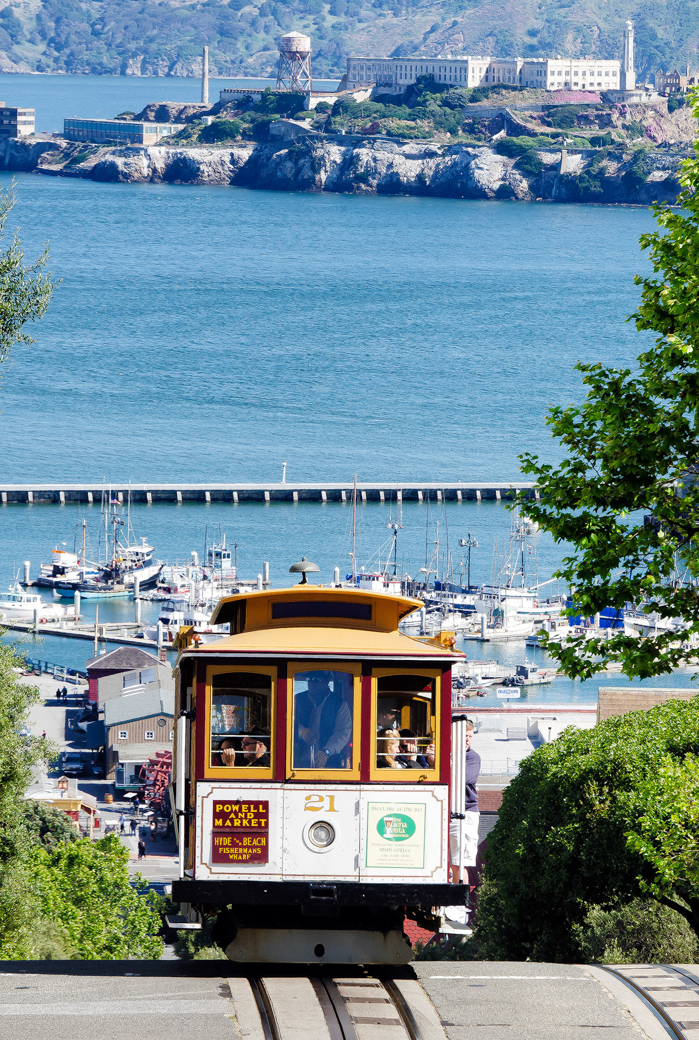 San Francisco's famous cable cars take passengers, on this line, along Hyde St. from Fisherman's Wharf.  In the background is the ominous Alcatraz Prison and fishing boats of Fisherman's Wharf.