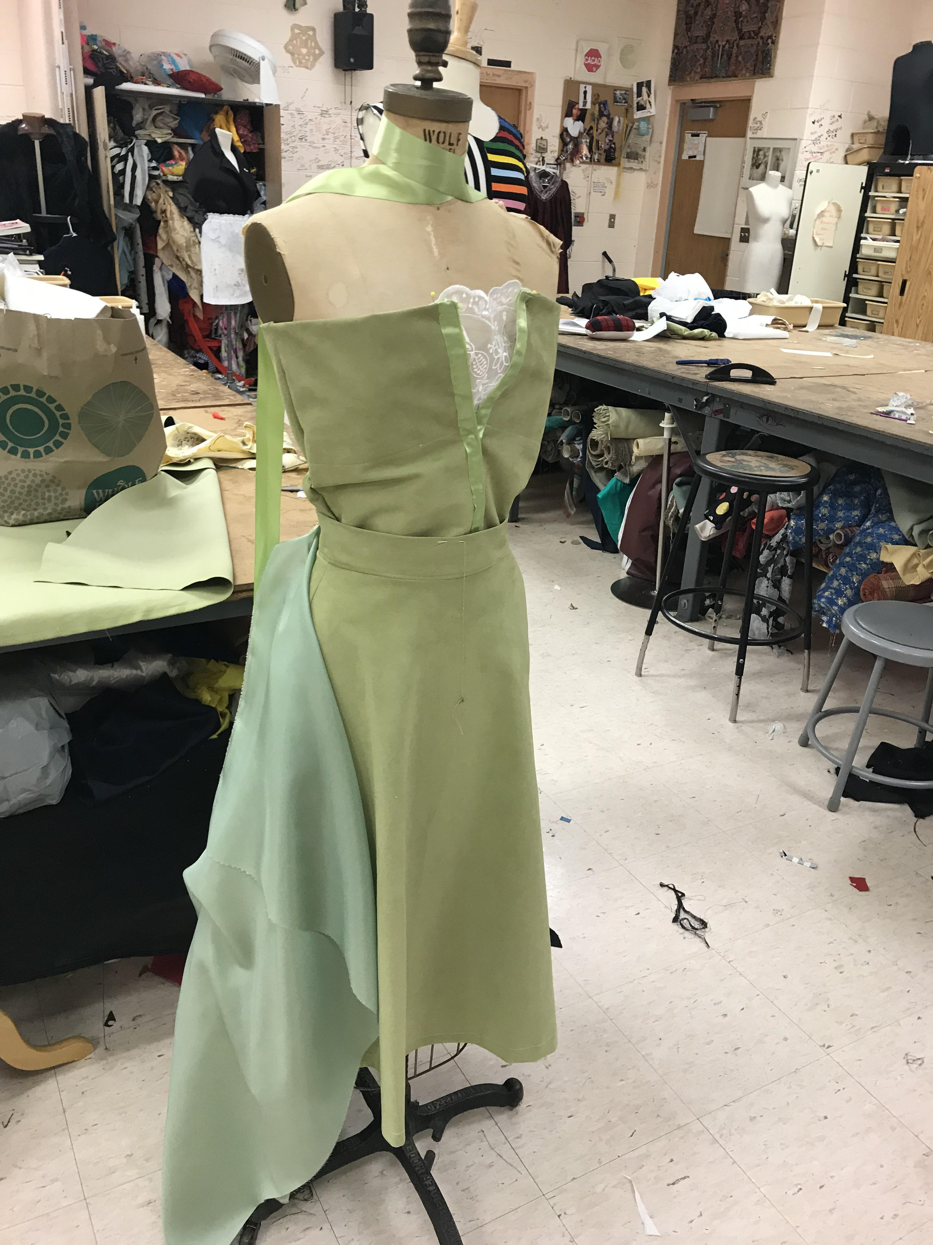 1. For the dress I chose a green suede that matched the hue of the painting, Bridge Over Water Lilies. I first created the bodice by selecting a pattern for a strapless top that fastened at the front of the bodice. This dress is composed of two pieces, so I used a separate pattern for the skirt. To create the top, I measured the inner lining to the fit of the mannequin I would use for my jury and pinned it to the form. Then creating the outer lining, I cut another bodice with 1/2 inch of the inner lining. Because this bodice would fasten at the front, I selected ribbon that was a similar colour to the palette of the painting. I sewed the outer and inner linings together and hemmed the front, stitching the ribbon the the ends of the fabric where I marked where the clasps would go to fit the mannequin properly.