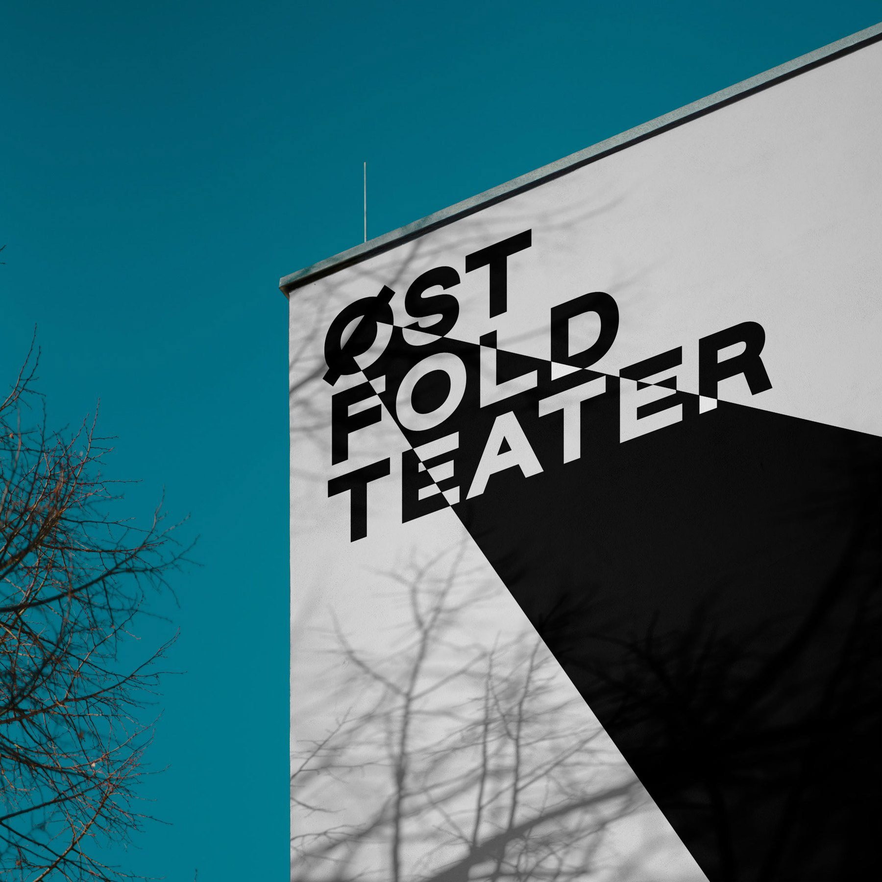 Østfold Teater-logo med lyskjegle i sort/hvitt på gavlvegg