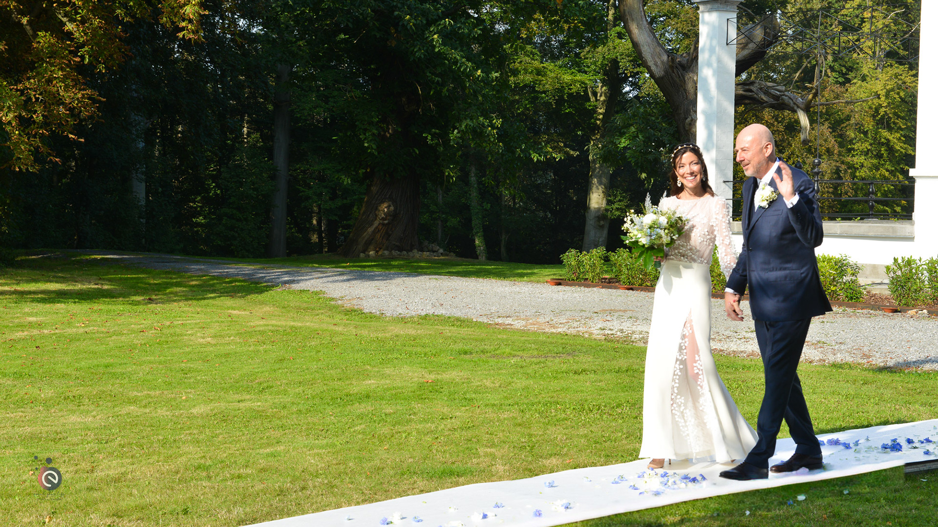 Entrée des mariés sur un tapis blanc fleuri lors de la cérémonie en extérieur de Nicoleta et Frank – organisation par event your life.
