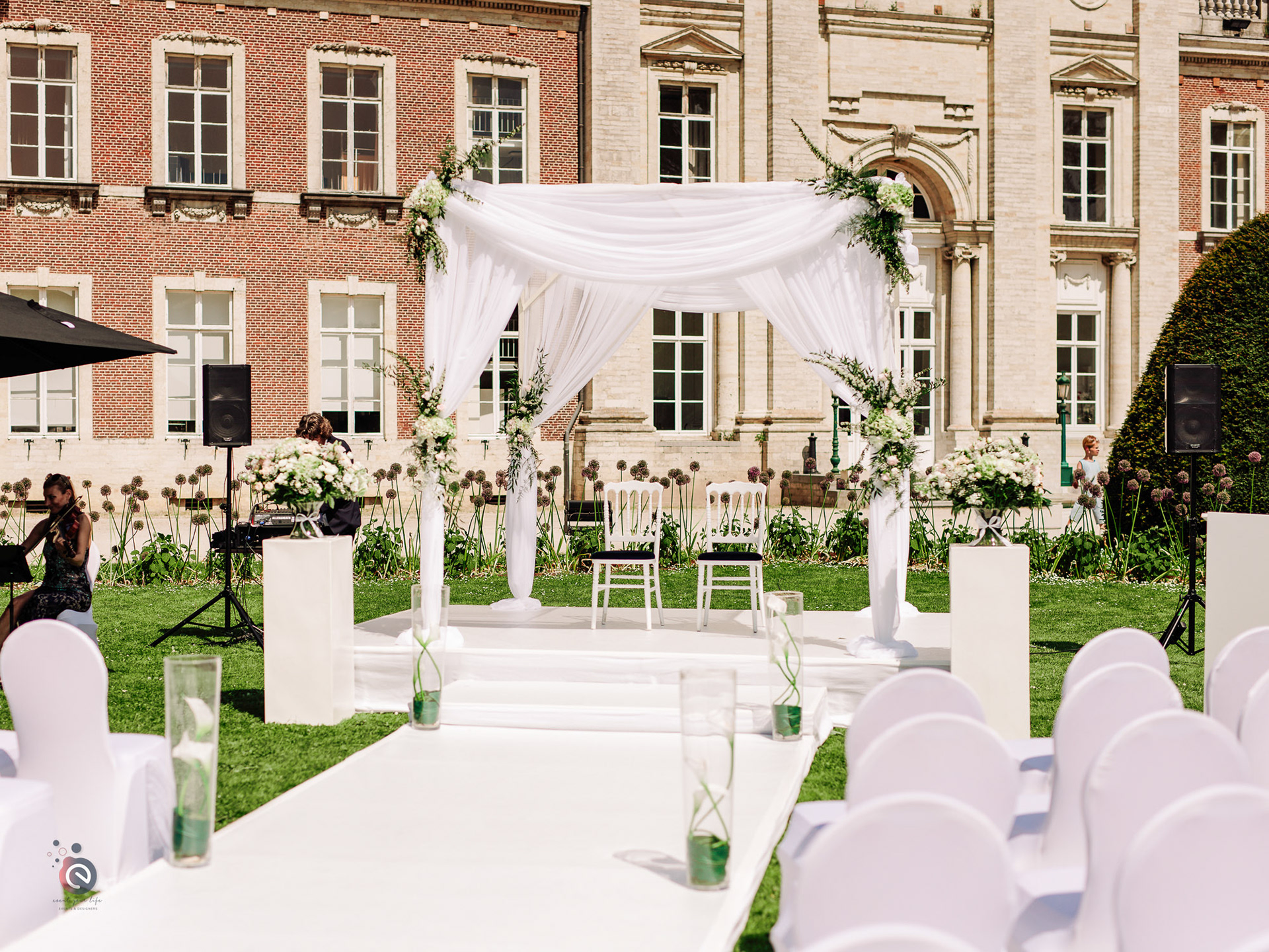 Arche de mariage décorée de voilages blancs devant un château — location décoration mariage en Belgique
