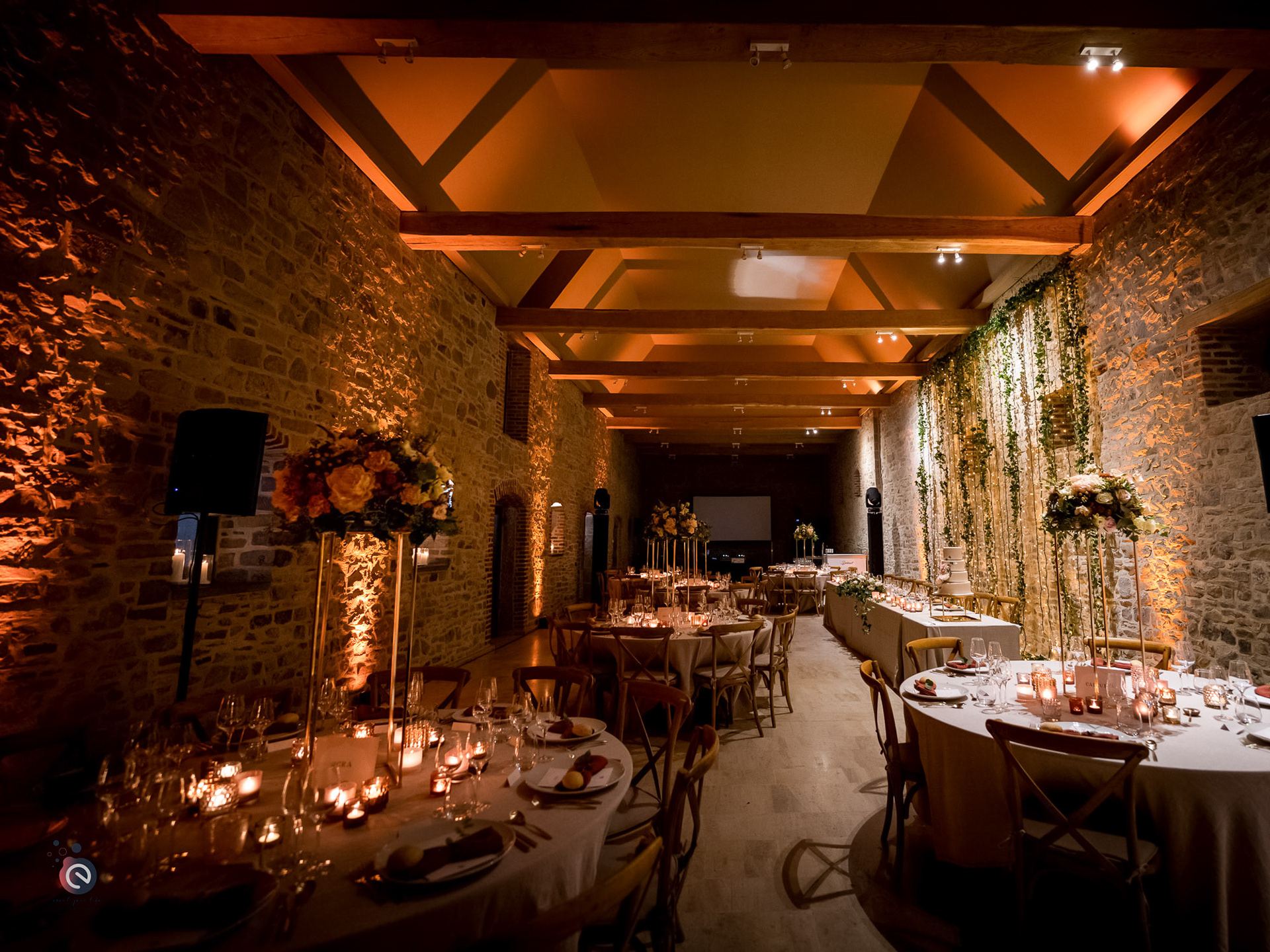 Ambiance chaleureuse de mariage avec bougies et photophores créant une atmosphère intimiste en salle.