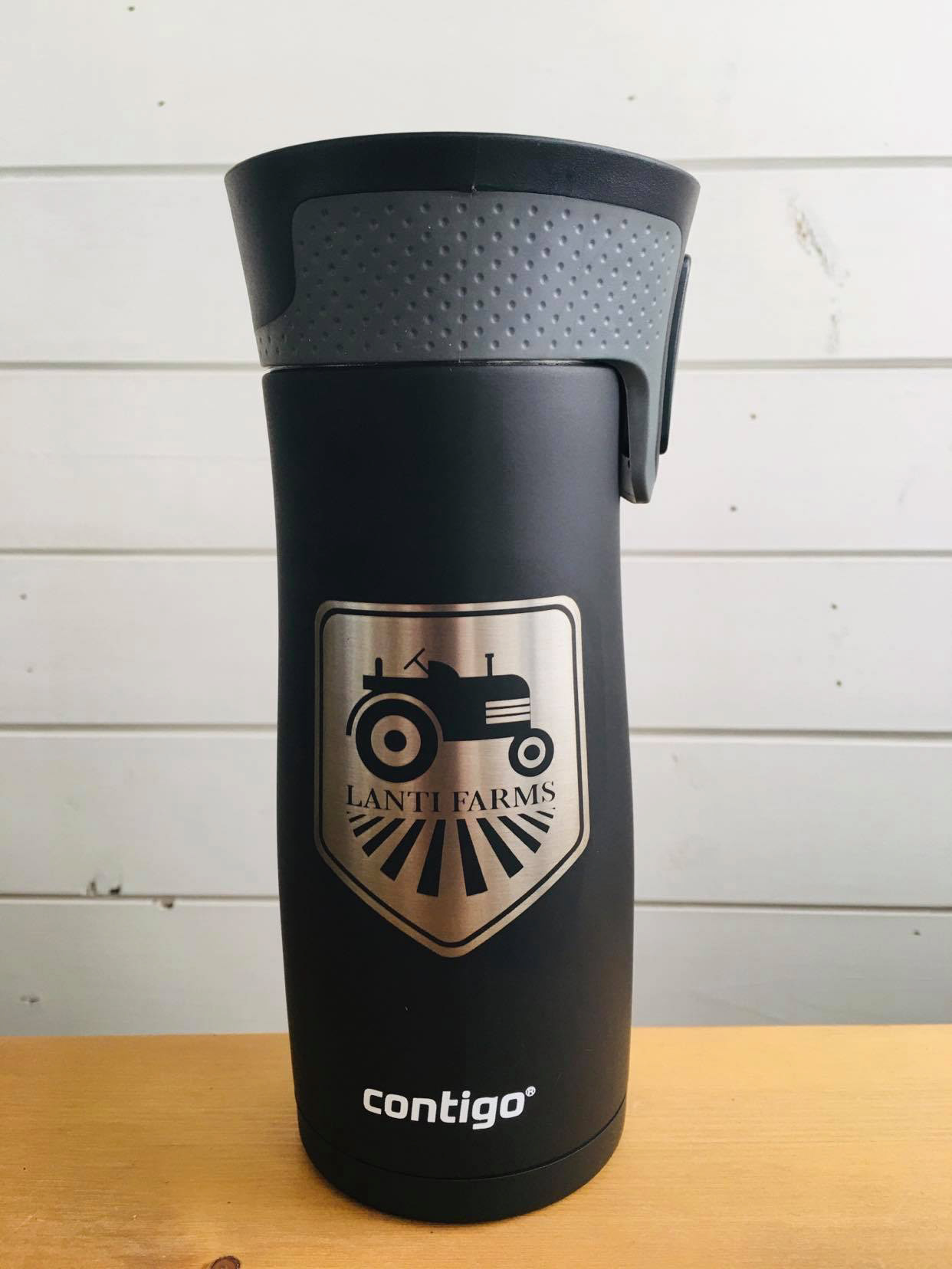 Gold crest logo with black tractor Lanti Farms on black water bottle