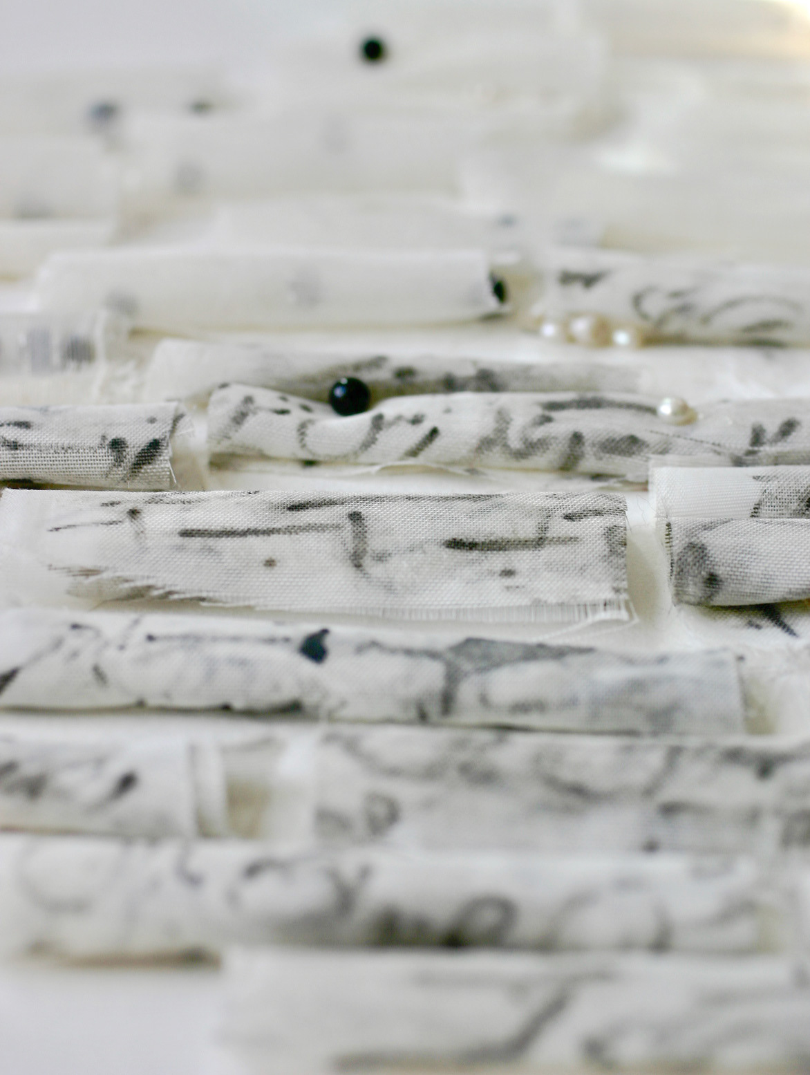 close up of artwork 37 Fabric Scrolls The black beads and white pearls—partially veiled inside and around the scrolls