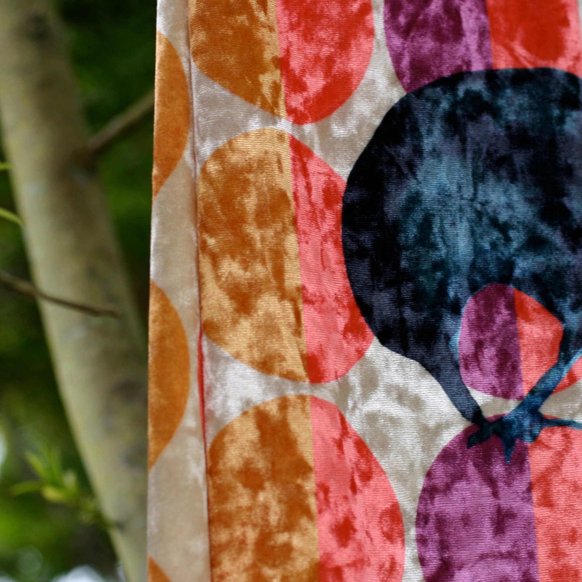 Close-up view of the velour scarf featuring an illustration of a raven in shades of black moonstone and blue onyx. The ravens are perched on top of multi-colored dots.