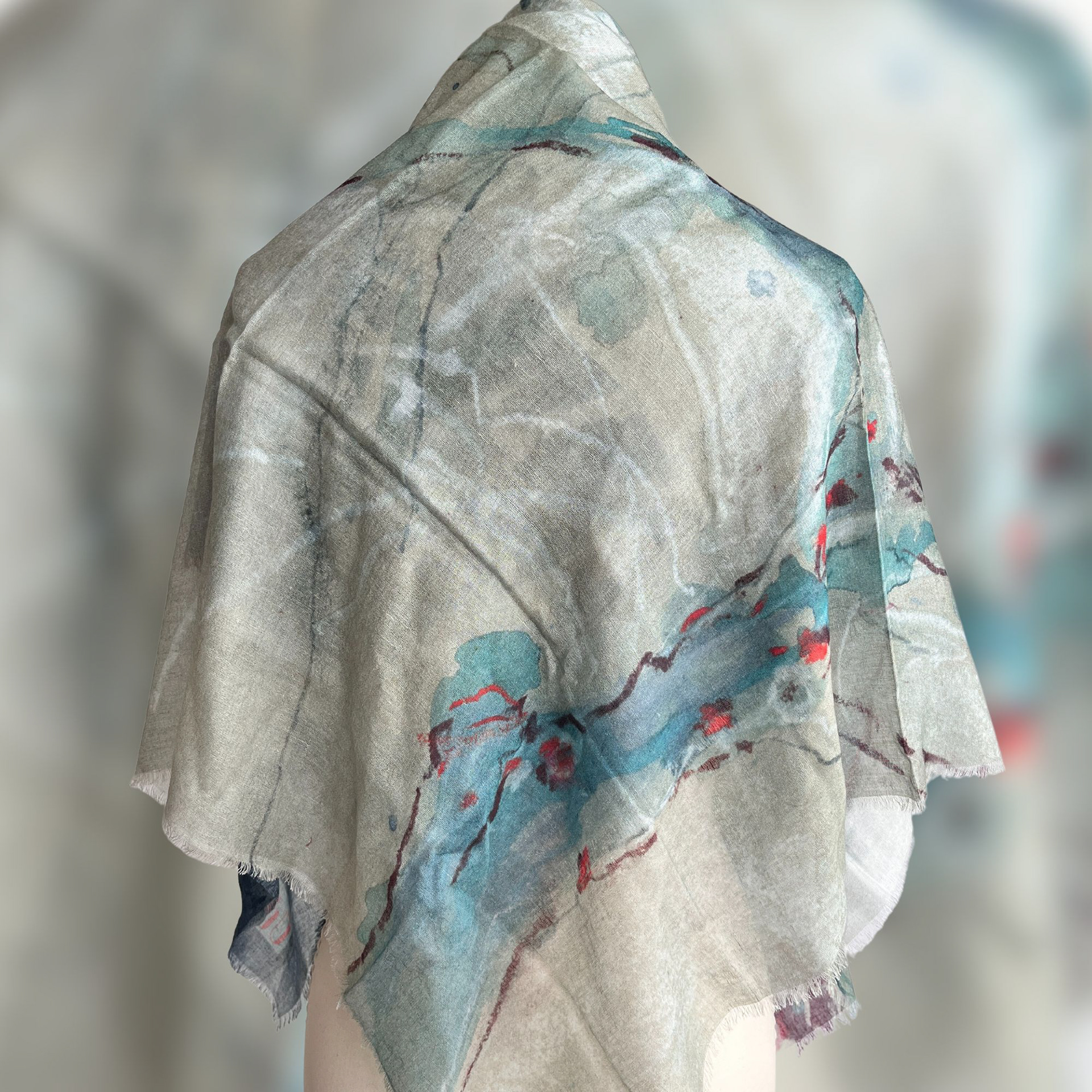 Close-up view  of hanging textile wall art: vibrant cypress tree illustration with sunlight filtering through branches. Colors range from silvery teals to deep indigo, with warm sienna red accents.