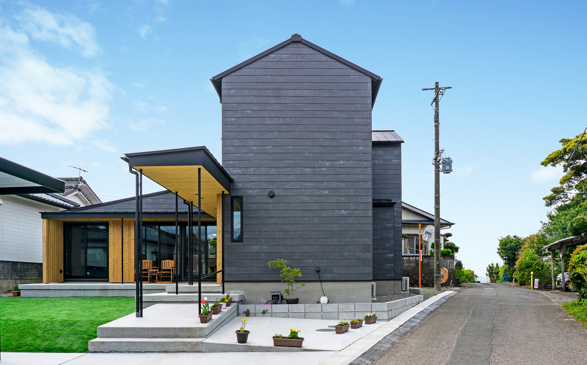 セメント板を利用した外壁　独特な白華と下見張りの陰影がやわらかくも特徴ある風景をつくる