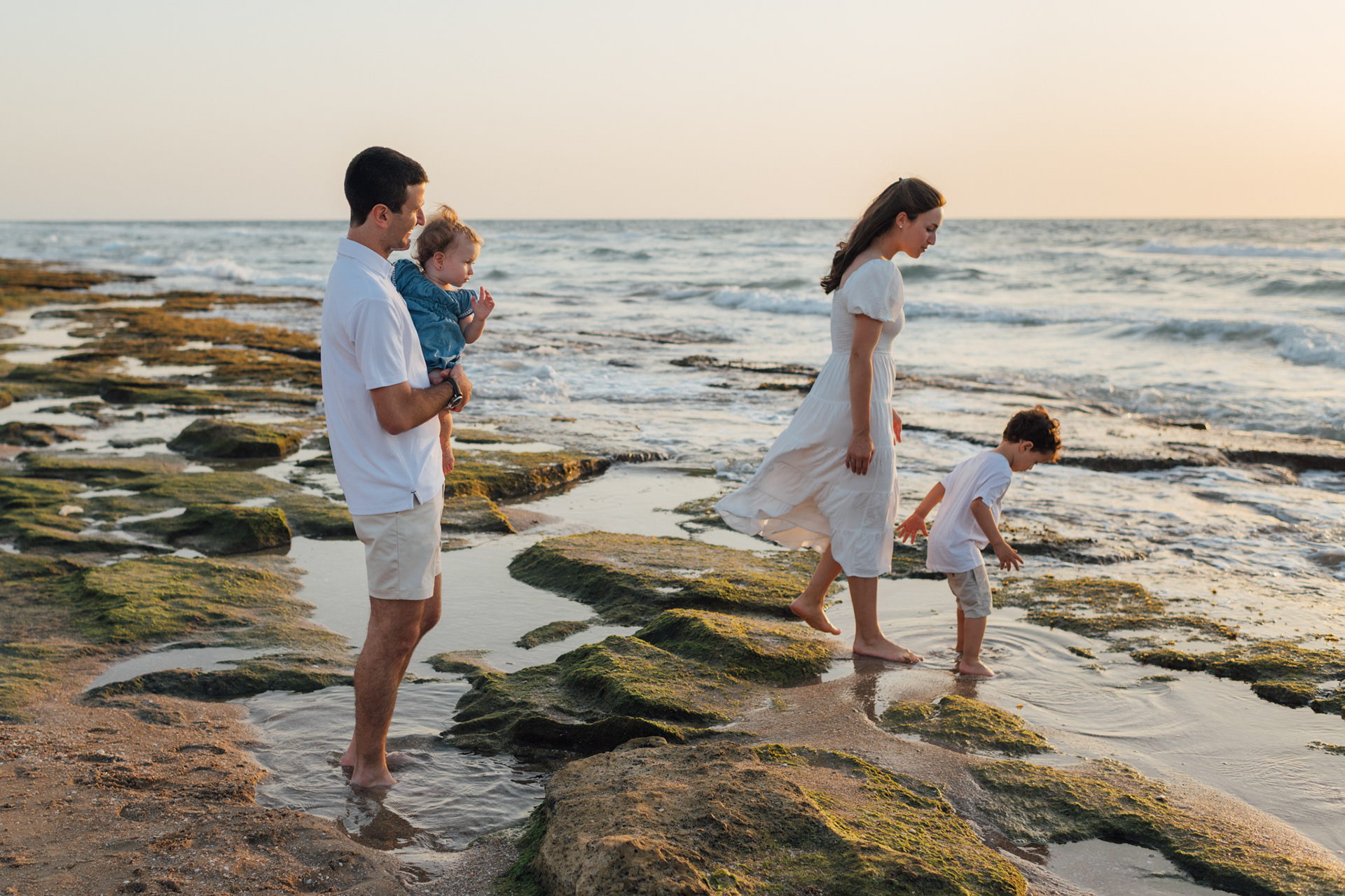 Family looking at the sea on a beautiful rocky beach at sunset