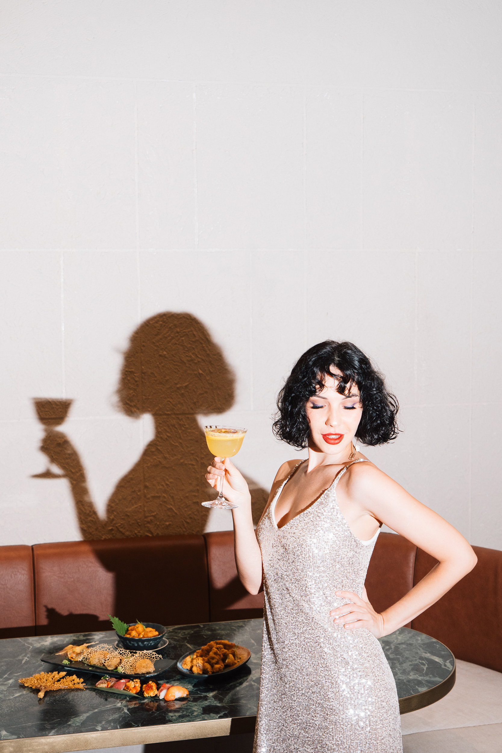 Model poses with cocktail and Japanese food