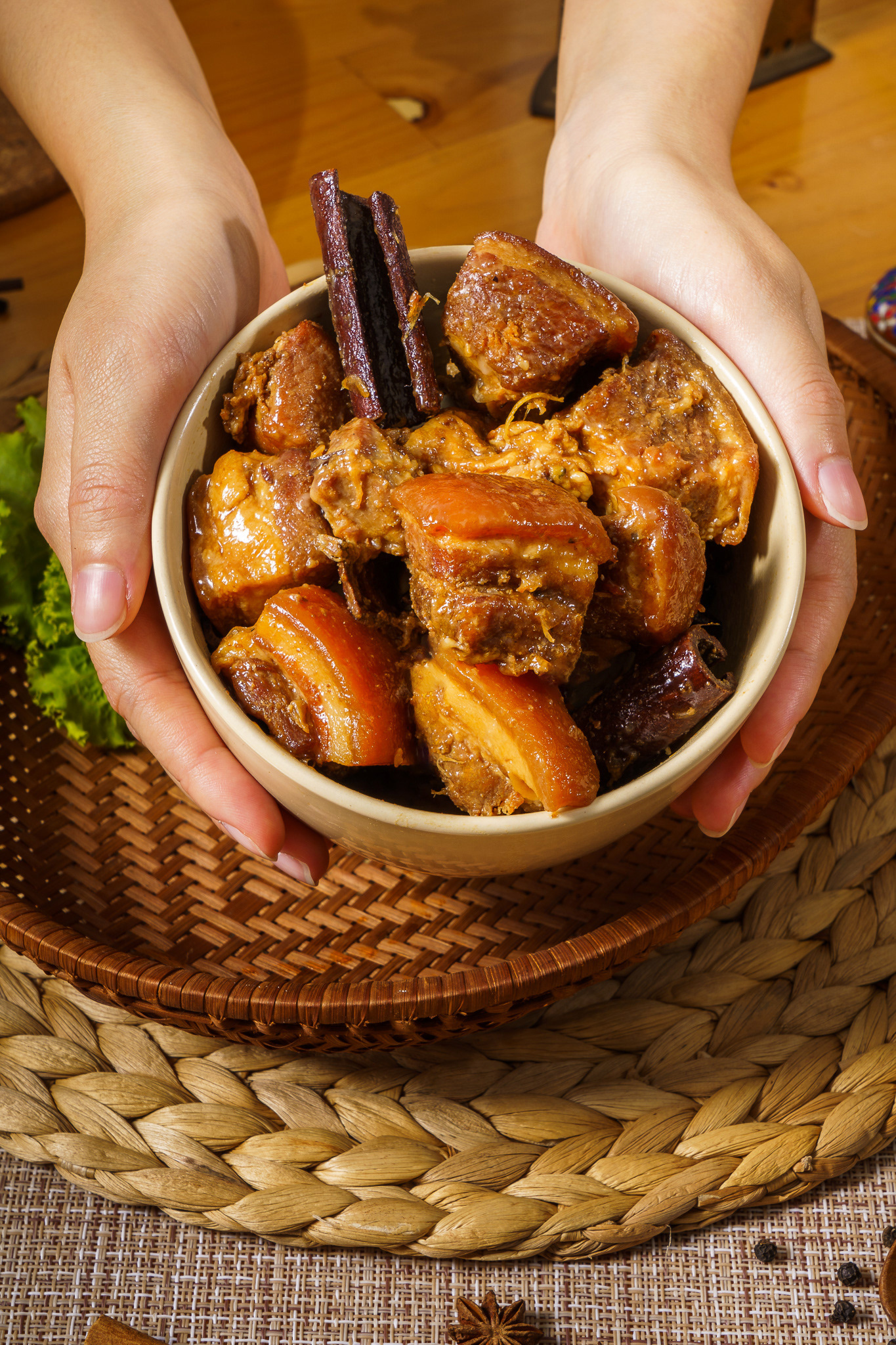 Female hand with Thai Pa-Lo stewed pork in white bowl