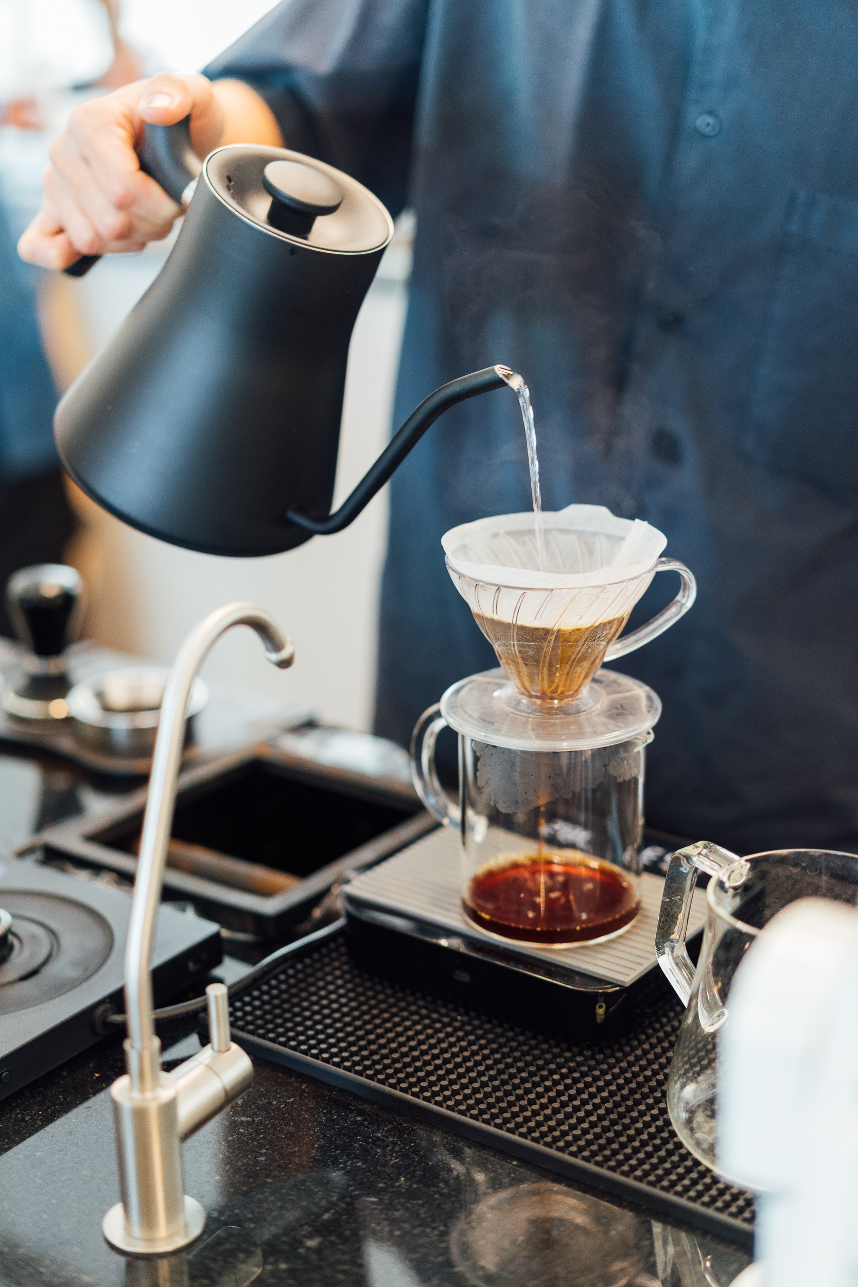 A barista is dripping coffee in the shop.