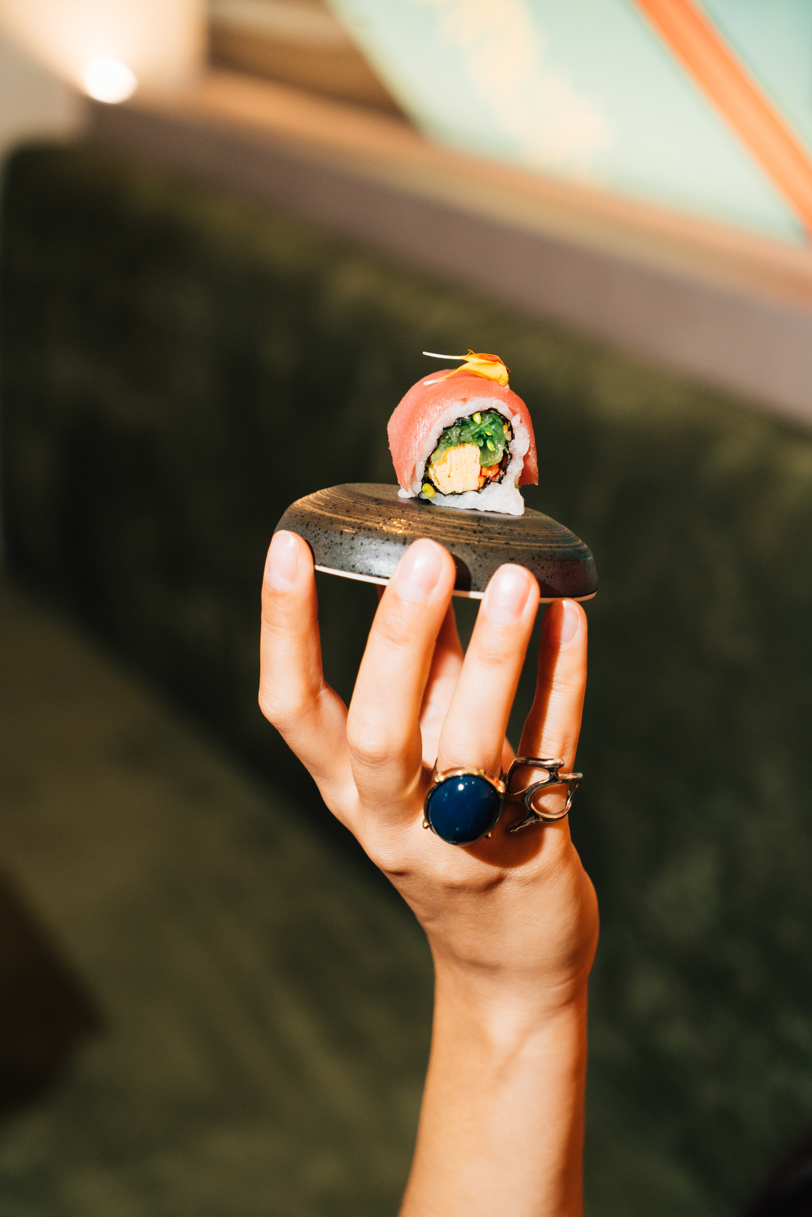 Creative photography of sushi by placing it on a dipping bowl and holding it up.