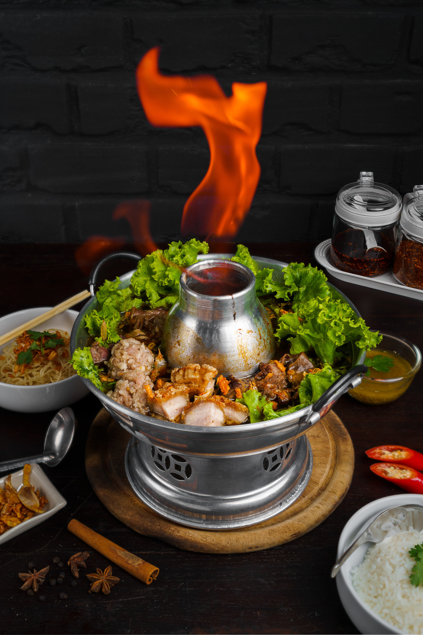 Thai pork soup with braised pork, crispy pork, pork tripe, meatball and vegetable on fire hot pot with wooden table
