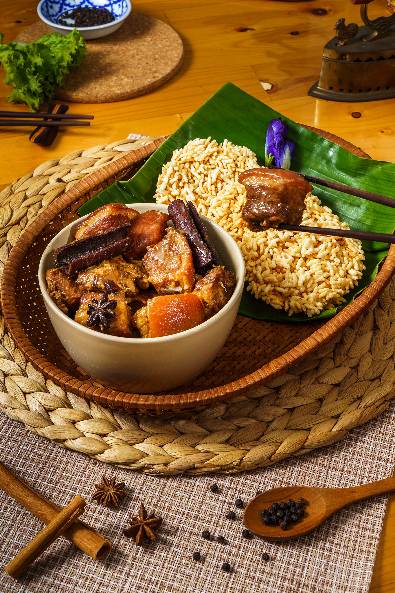 Hand of people using wood chopsticks holding stewed pork in white bowl with Thai rice cracker 