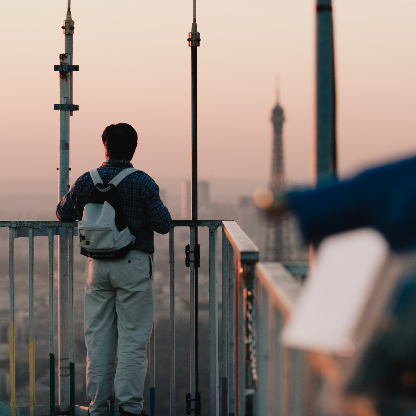 Un homme sur le toit de la Tour Montparnasse regarde la Tour Eiffel.